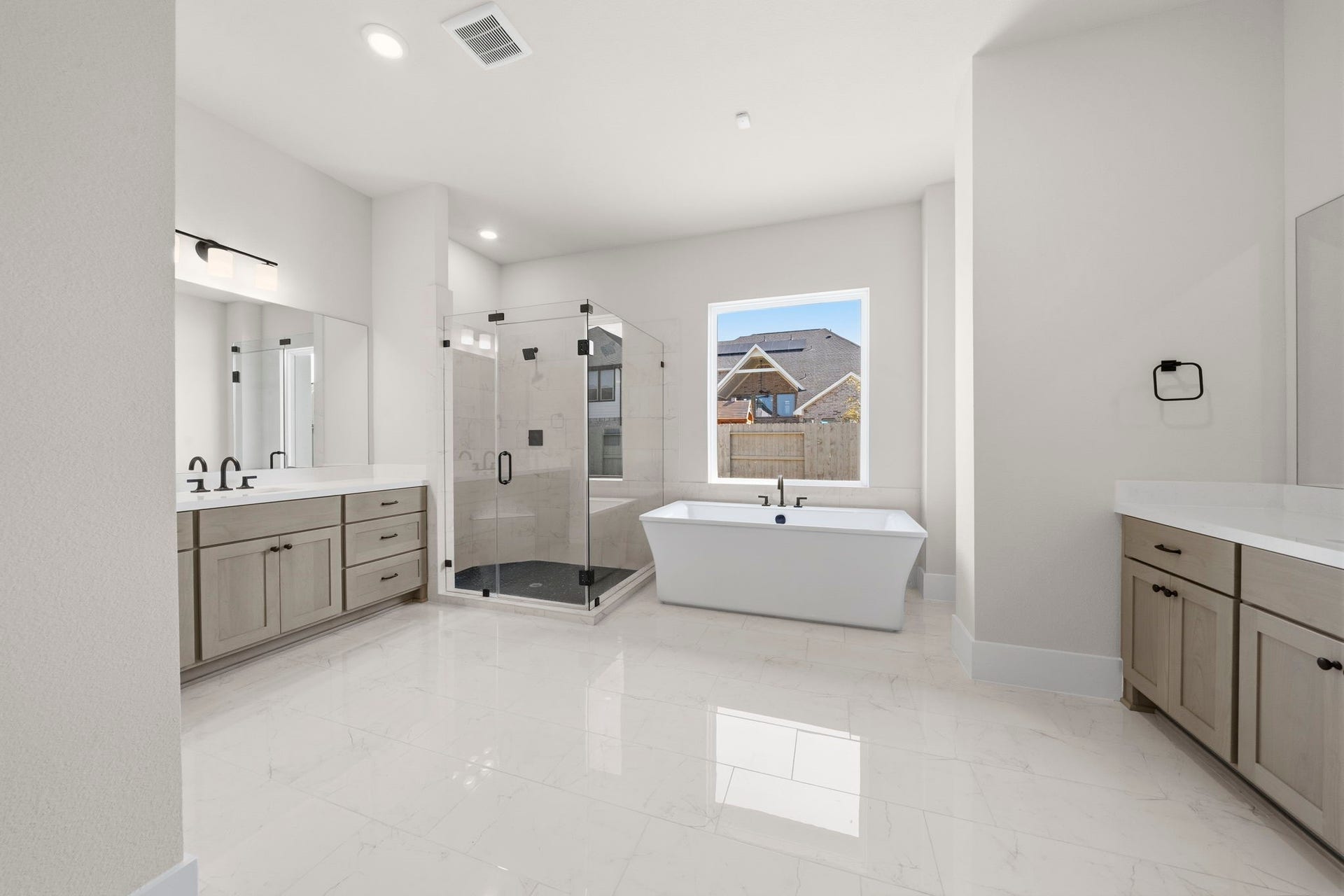 Home Spa, spacious, modern bathroom features a freestanding tub, an elegant glass-enclosed shower, dual vanities with ample storage, and large windows for natural light.