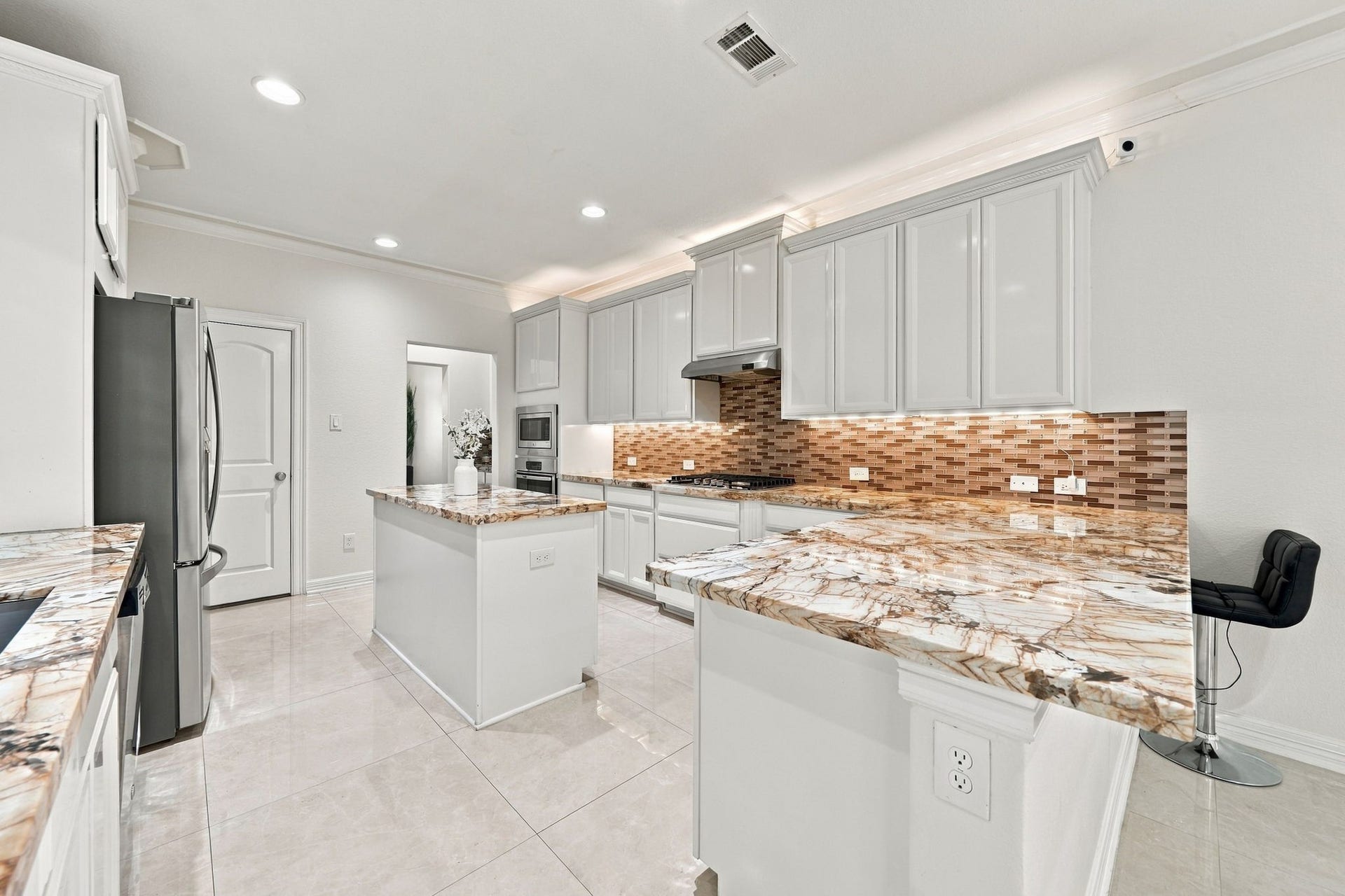 5411 Oban Terrace Lane, Sugar Land, TX 77479 Beautiful stone countertops, elegant white cabinetry, and a mosaic tile backsplash make this kitchen a ideal combination of style, functionality, and everyday comfort.