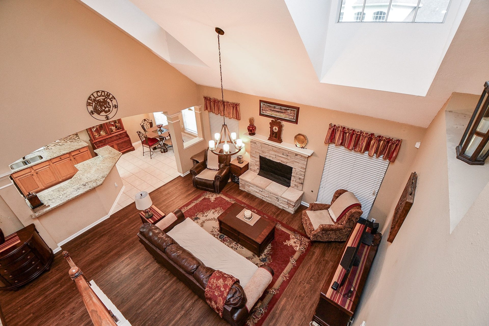 A view that really showcases the home's open design! From the upstairs overlook, you can appreciate the soaring ceilings, beautiful stone fireplace, and seamless connection between the family room, kitchen, and breakfast area.