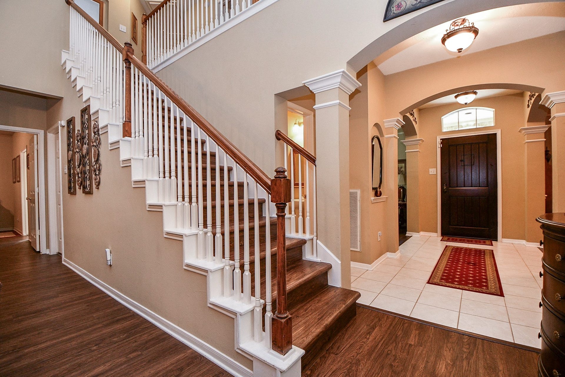 Architectural details give this home its distinctive character. The wood staircase, contrasting white balusters, and graceful archways create an inviting transition between the home's main living spaces and upstairs rooms.