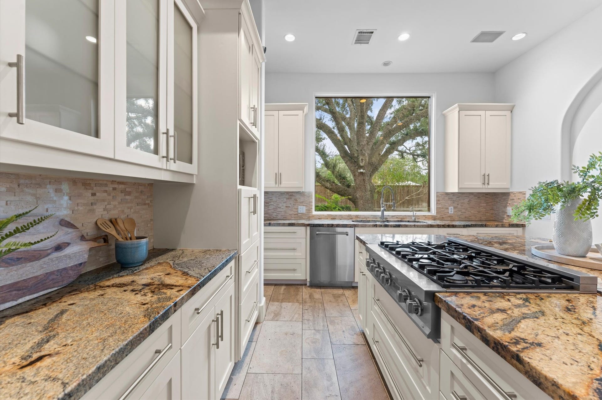 5135 Longmont Drive, Houston, TX 77056 Alternate kitchen view featuring an expansive island with breakfast bar, built-in wall ovens, double-basin sink, granite countertops, and freshly painted cabinetry.