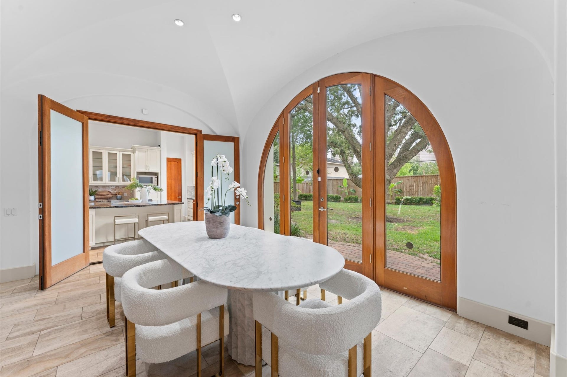 5135 Longmont Drive, Houston, TX 77056 Warm architectural details define the breakfast room, including travertine flooring, plaster walls, a vaulted plaster ceiling, and arched glass doors overlooking the loggia, summer kitchen, pergola, and pool.