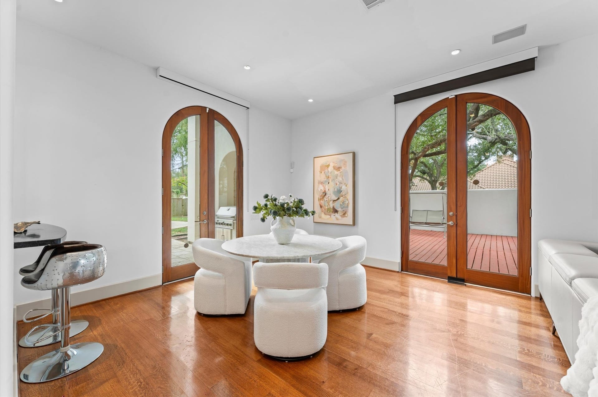 5135 Longmont Drive, Houston, TX 77056 A light-filled gallery sitting area nestled beside the entertaining bar, featuring elegant arched mahogany doors that open to the outdoor patio. An inviting setting for morning coffee, intimate conversation, or effortless entertaining, with seamless indoor-outdoor flow.