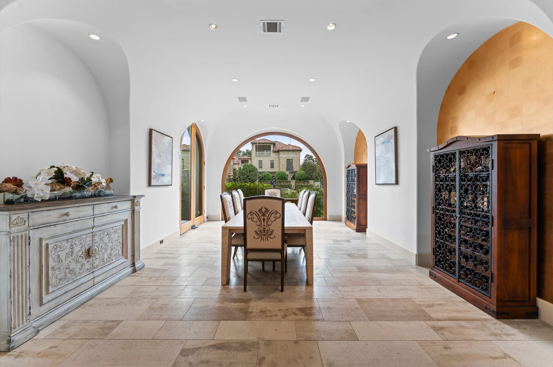 5135 Longmont Drive, Houston, TX 77056 An elegant formal dining room distinguished by floor-to-ceiling arched windows, abundant natural light, imported travertine flooring, mahogany baseboards, recessed lighting, and exquisite gold-leaf accent walls.