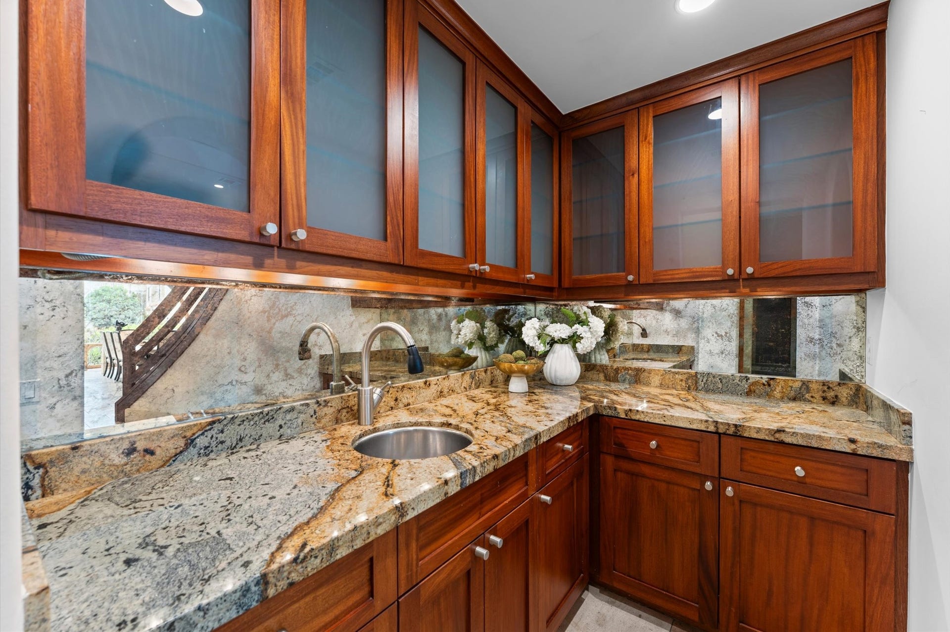 5135 Longmont Drive, Houston, TX 77056 A full-service butler's pantry off the kitchen offers extensive storage, custom mahogany cabinetry, granite countertops, and a dedicated sink, providing an elegant and functional extension of the gourmet kitchen.