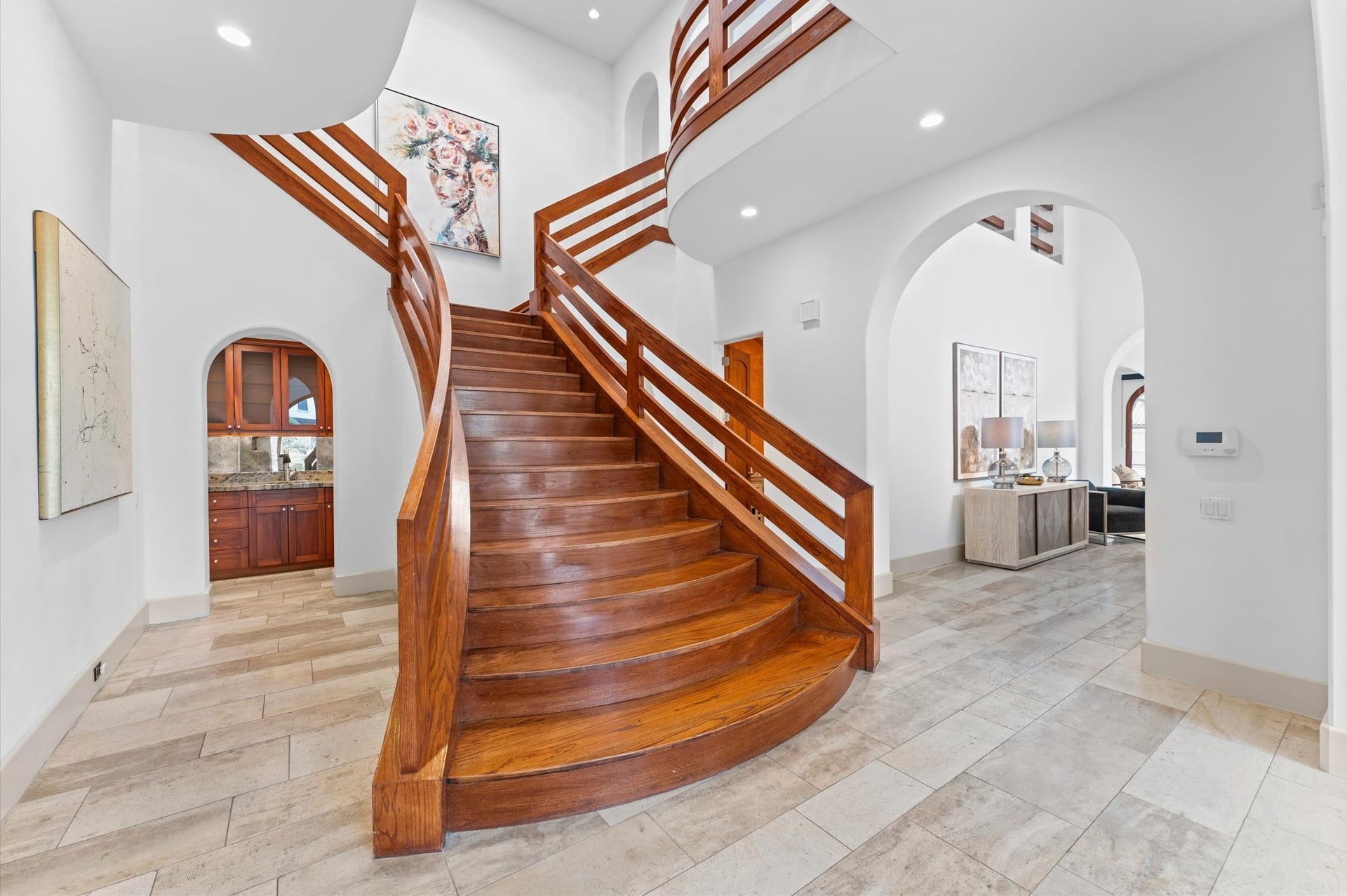 5135 Longmont Drive, Houston, TX 77056 A striking bifurcated mahogany staircase rises from the double-height reception gallery, branching toward the upper gallery and connecting the private primary suite and secondary bedroom wings.