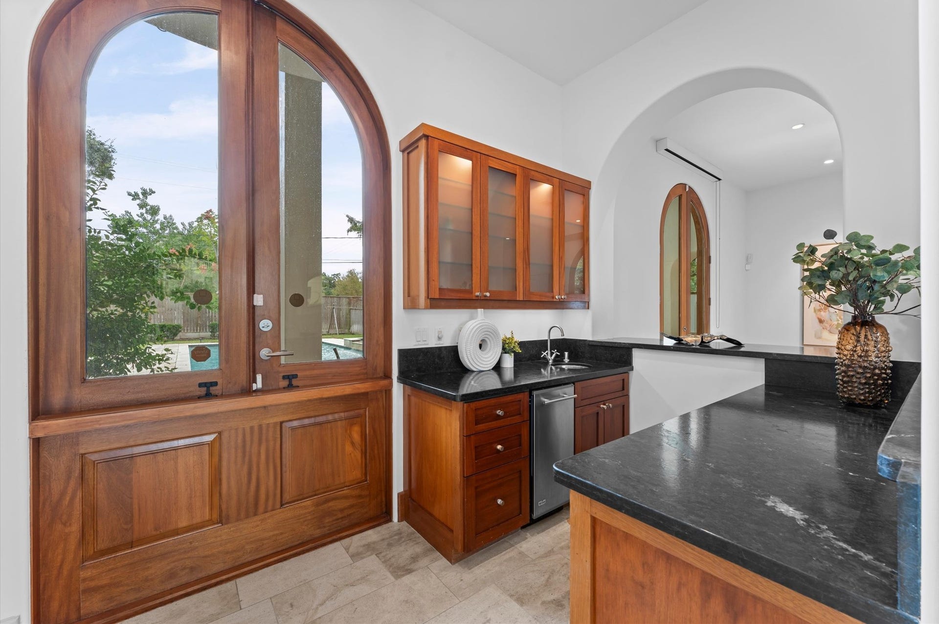 5135 Longmont Drive, Houston, TX 77056 A beautifully appointed wet bar features black marble countertops, a beverage chiller, ice maker, bar sink, and abundant storage. Operable service windows connect the bar to the outdoor kitchen and dining areas.