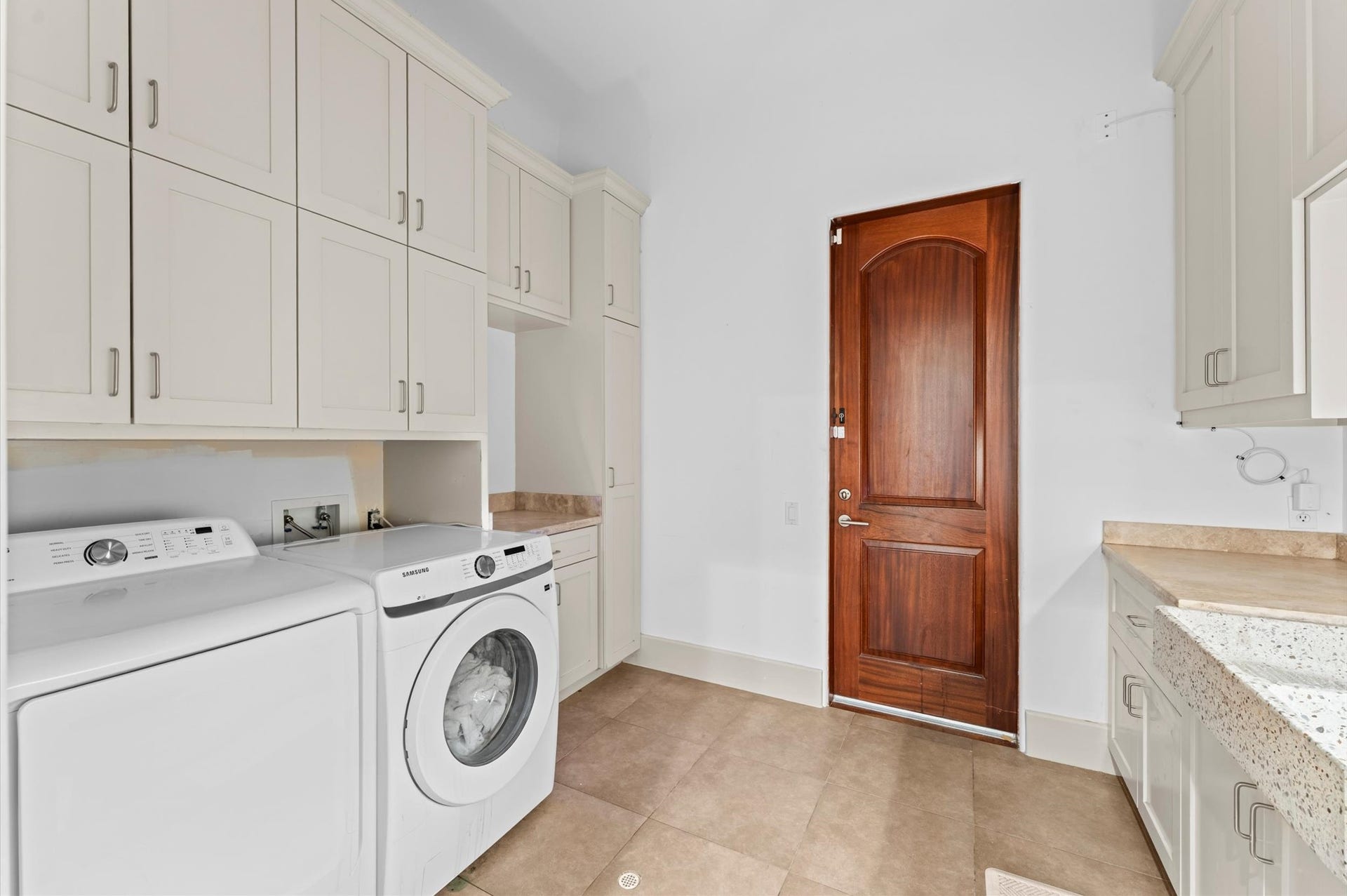 5135 Longmont Drive, Houston, TX 77056 A spacious laundry room with custom built-in cabinetry and convenient exterior access to the side patio near the garage, combining functionality with everyday convenience.
