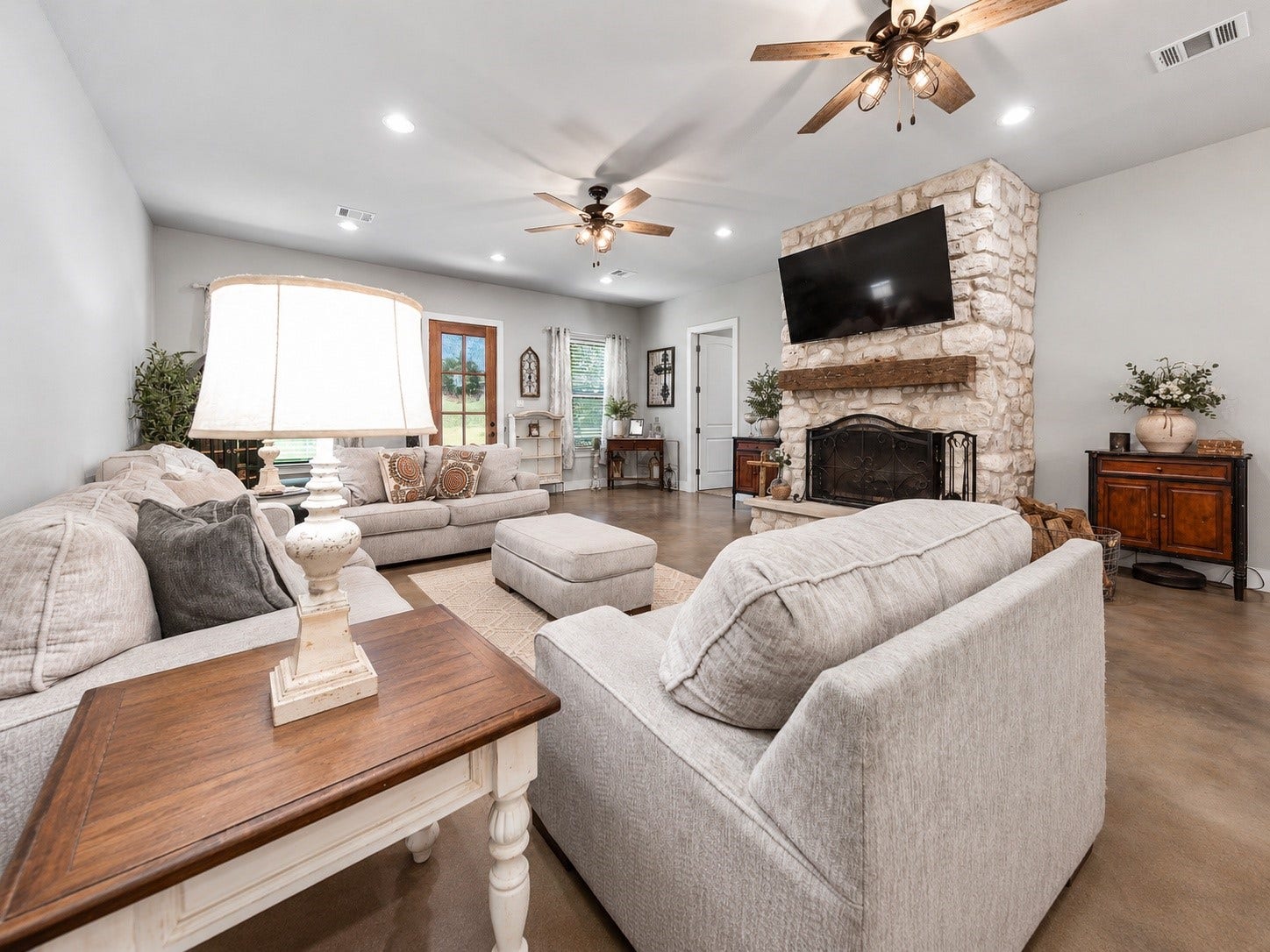 3295 Fm 524 Road, Sweeny, TX 77480 Family room seating area facing the stone fireplace, with ceiling fans and stained concrete floors. This photo may be edited using AI tools.