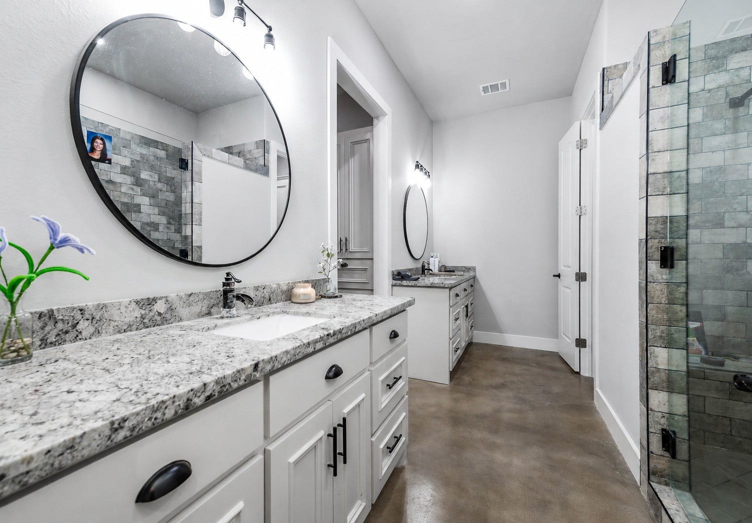 3295 Fm 524 Road, Sweeny, TX 77480 Primary bathroom with double vanity, granite countertops, round mirrors and a glass-enclosed walk-in shower. This photo may be edited using AI tools.