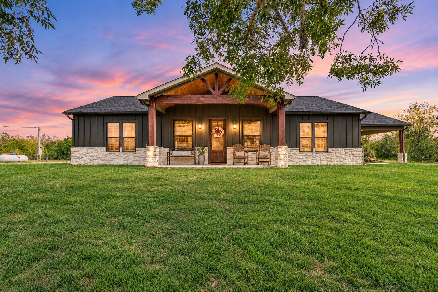 3295 Fm 524 Road, Sweeny, TX 77480 Front exterior at dusk of this 2022-built Sweeny, TX country home on 15.9 acres, with a covered front porch and board-and-batten siding. This photo may be edited using AI tools.