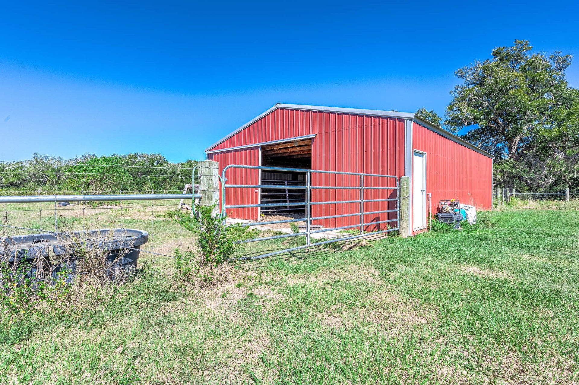 3295 Fm 524 Road, Sweeny, TX 77480 Red metal barn on the property, ready to be finished with stalls in the sizes of your choice. This photo may be edited using AI tools.