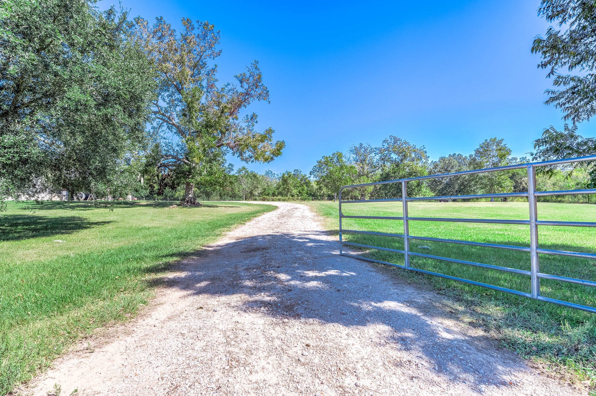 3295 Fm 524 Road, Sweeny, TX 77480 Gated gravel drive off FM 524 leading to the home through open pasture and mature trees. This photo may be edited using AI tools.