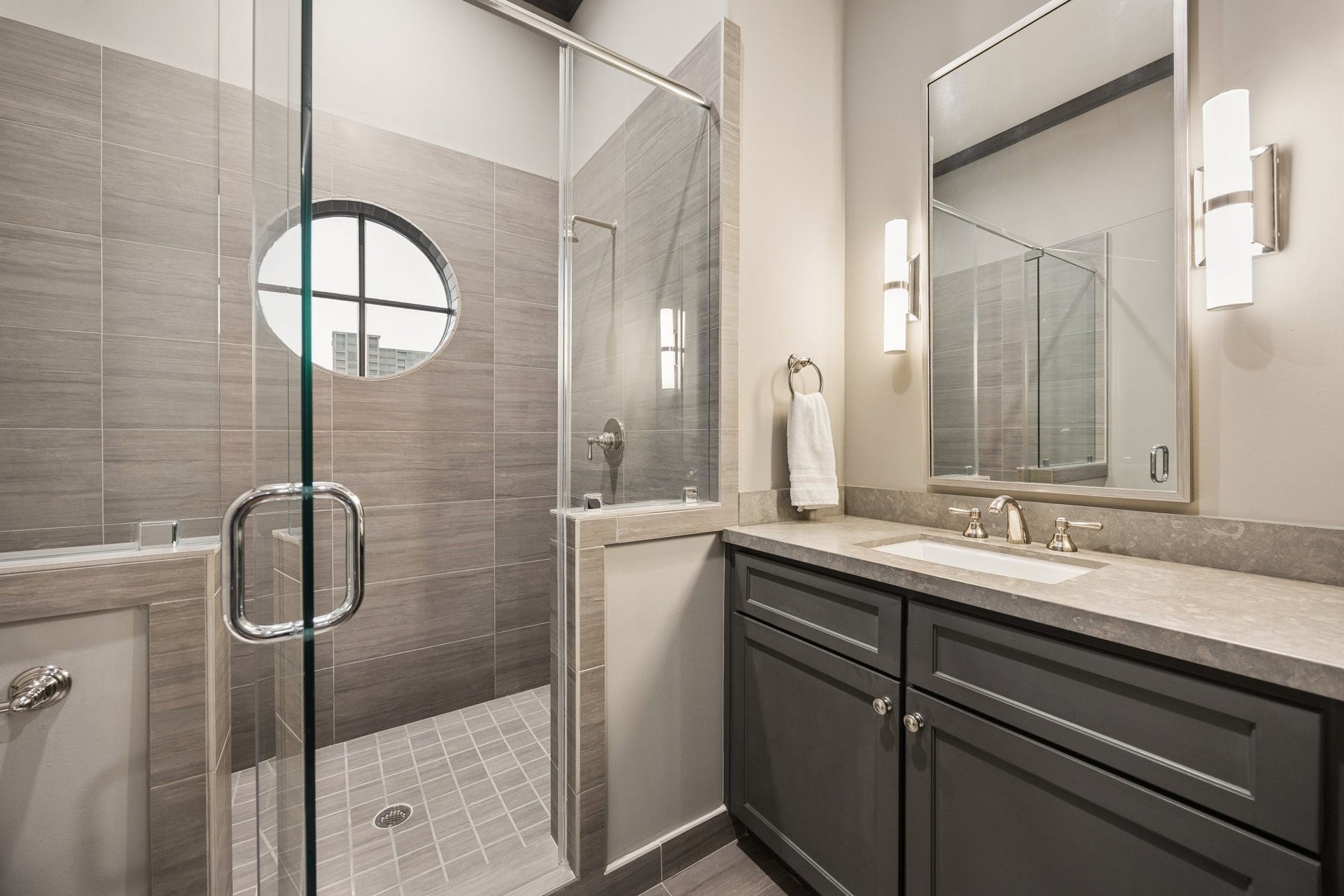 2131 Bancroft Street, Houston, TX 77027 Elegant fourth-floor full bathroom featuring a glass-enclosed walk-in shower, contemporary tilework, stone countertop, and a custom vanity. Conveniently located adjacent to the spacious game room, offering flexibility for use as a private guest suite.