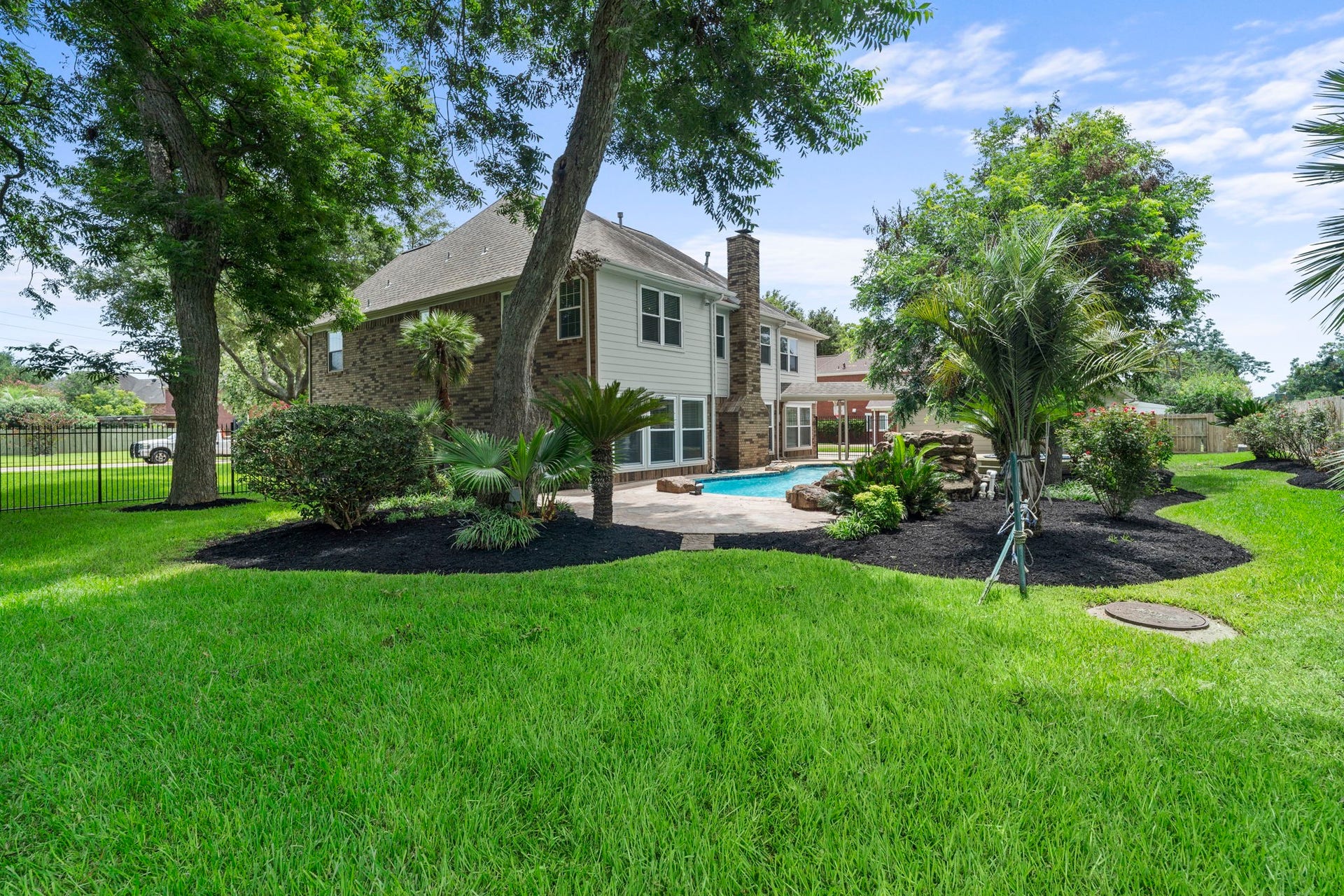 75 Stalybridge Street, Sugar Land, TX 77479 A beautifully landscaped backyard offers generous green space beyond the pool, with mature trees creating a picturesque setting for outdoor living.