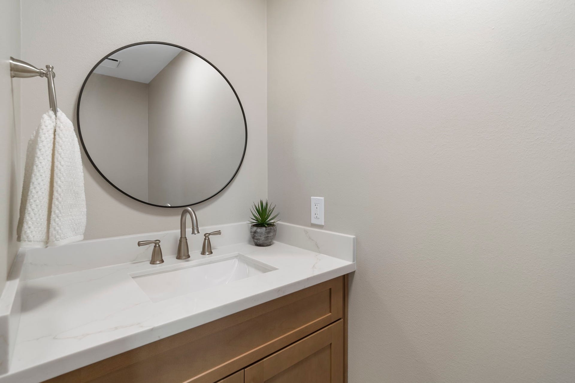 75 Stalybridge Street, Sugar Land, TX 77479 The updated powder bath features a sleek stone countertop, warm wood cabinetry & a modern round mirror for a clean, polished finish.