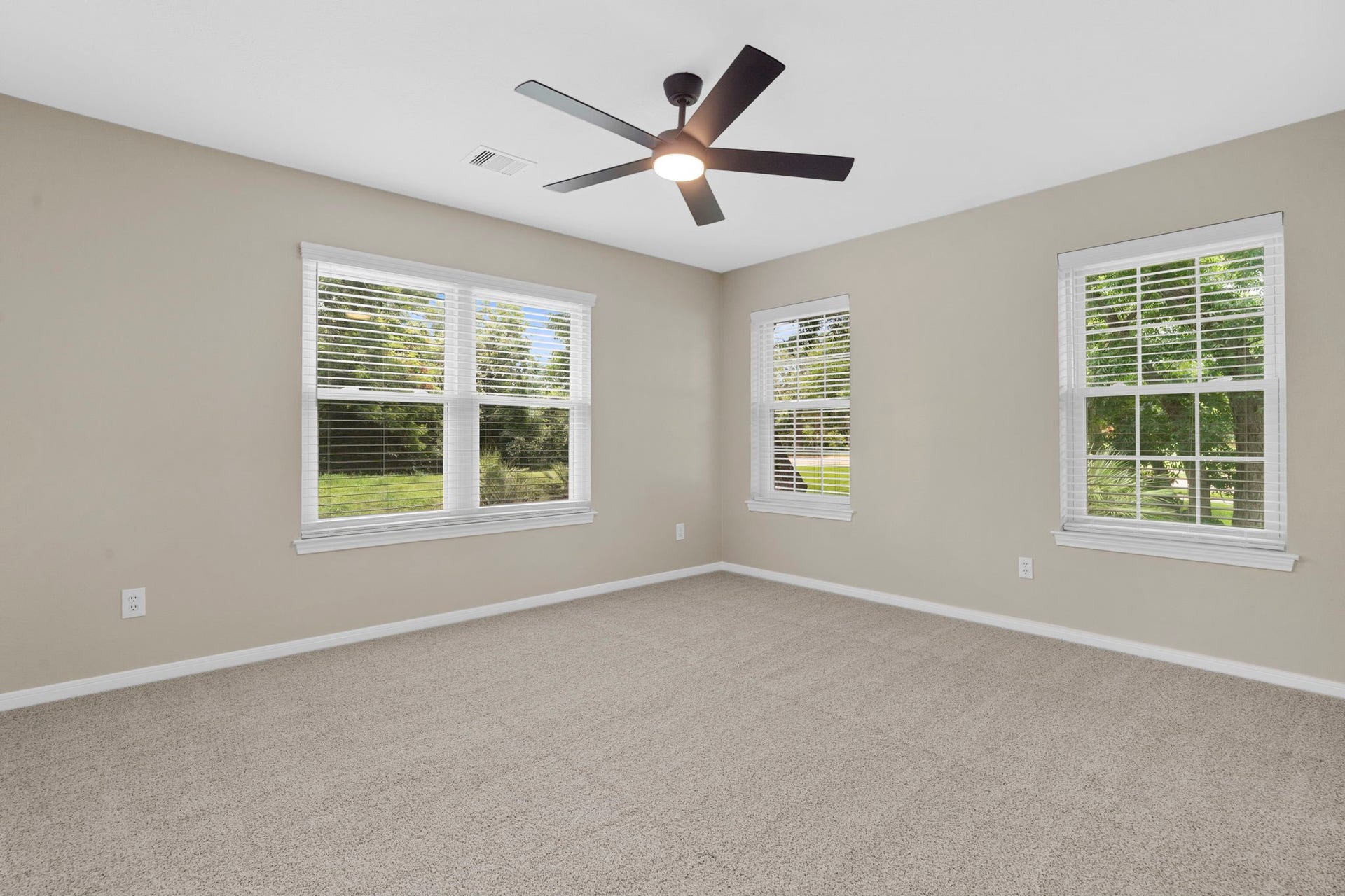75 Stalybridge Street, Sugar Land, TX 77479 A spacious secondary bedroom is filled with natural light from multiple windows, offering ample room for a comfortable sitting area or workspace.