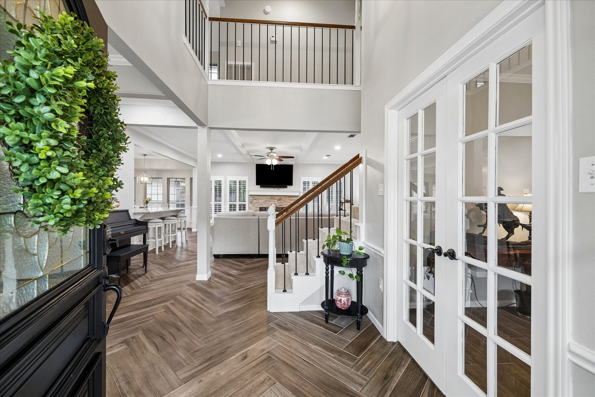 2411 Kings Lodge Drive, Kingwood, TX 77345 Elegant entryway featuring stylish herringbone flooring, a welcoming staircase, and an open view into the bright living area with high ceilings and modern finishes.