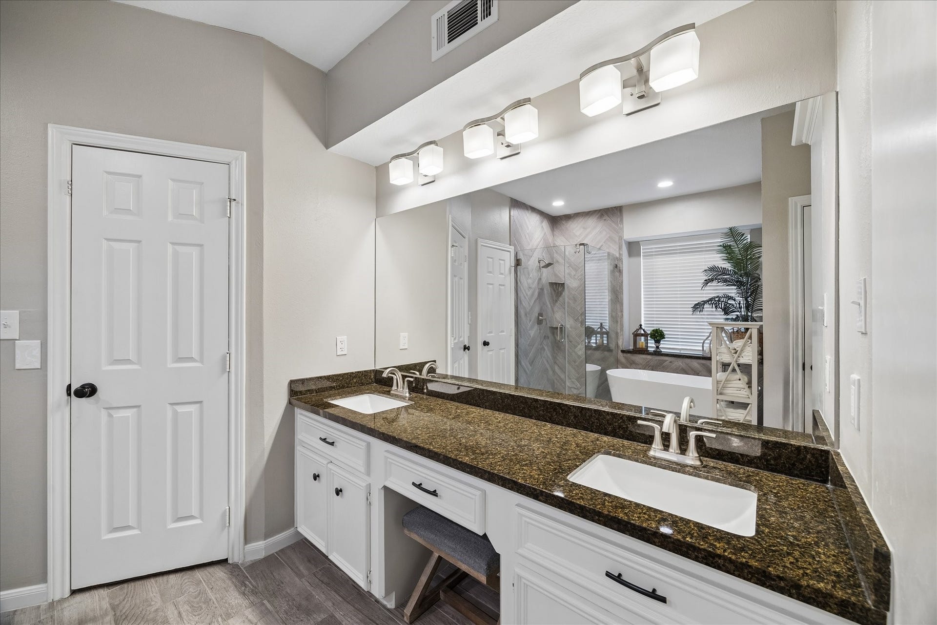 2411 Kings Lodge Drive, Kingwood, TX 77345 Spacious bathroom featuring a double vanity with granite countertops, elegant lighting, and a large mirror, complemented by a glass-enclosed shower and a stylish soaking tub, creating a serene retreat.