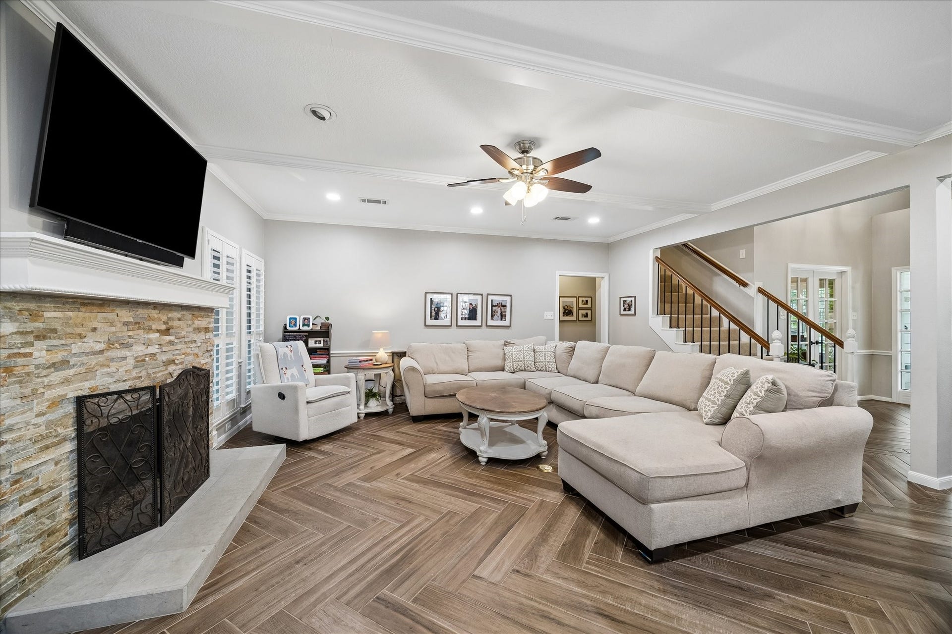 2411 Kings Lodge Drive, Kingwood, TX 77345 Spacious living room with elegant herringbone ceramic wood flooring, and a cozy stone fireplace, perfect for entertaining and family living.