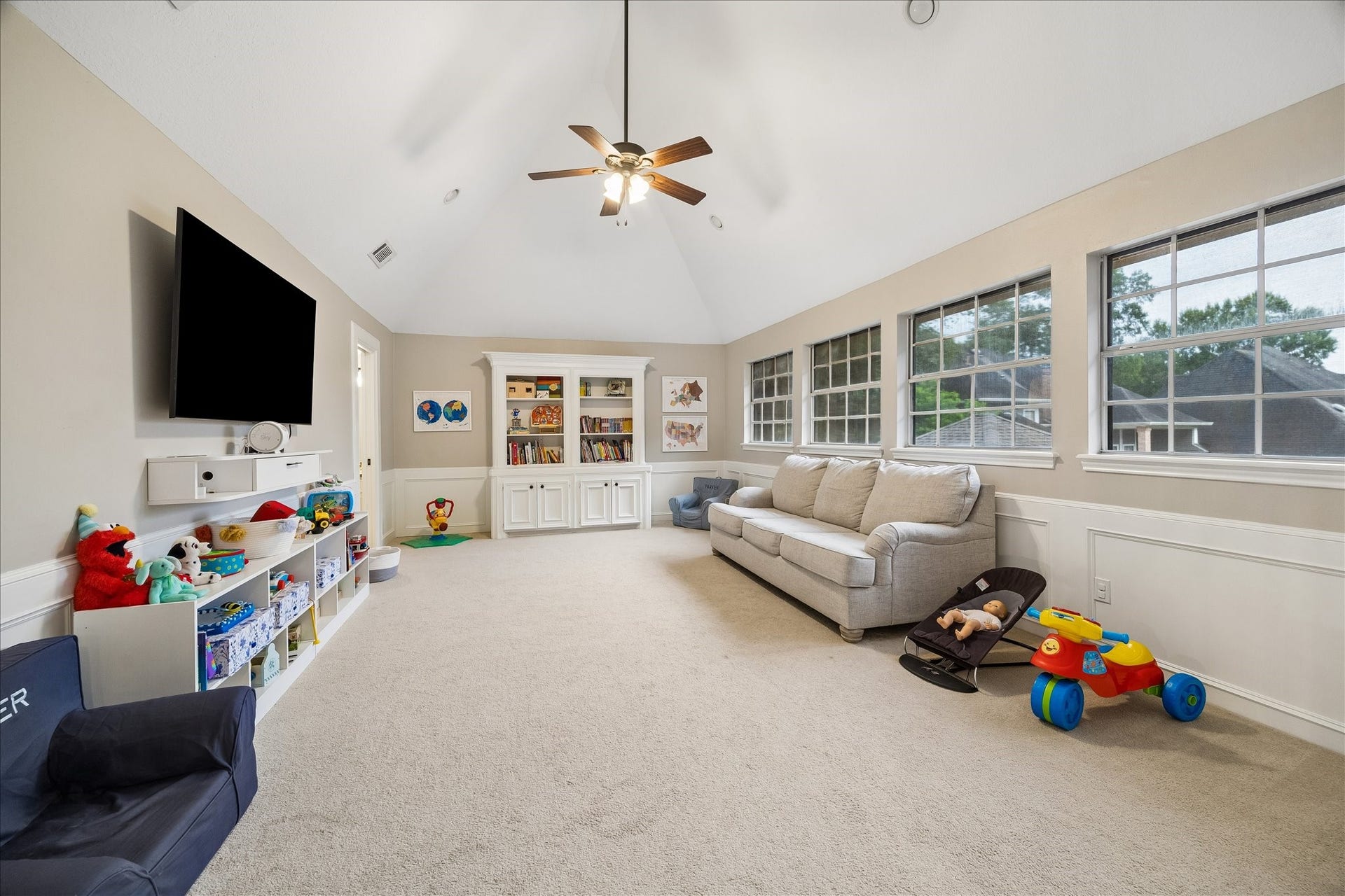 2411 Kings Lodge Drive, Kingwood, TX 77345 Spacious family room with abundant natural light, featuring large windows, built-in shelving, and a cozy seating area perfect for relaxation and play.