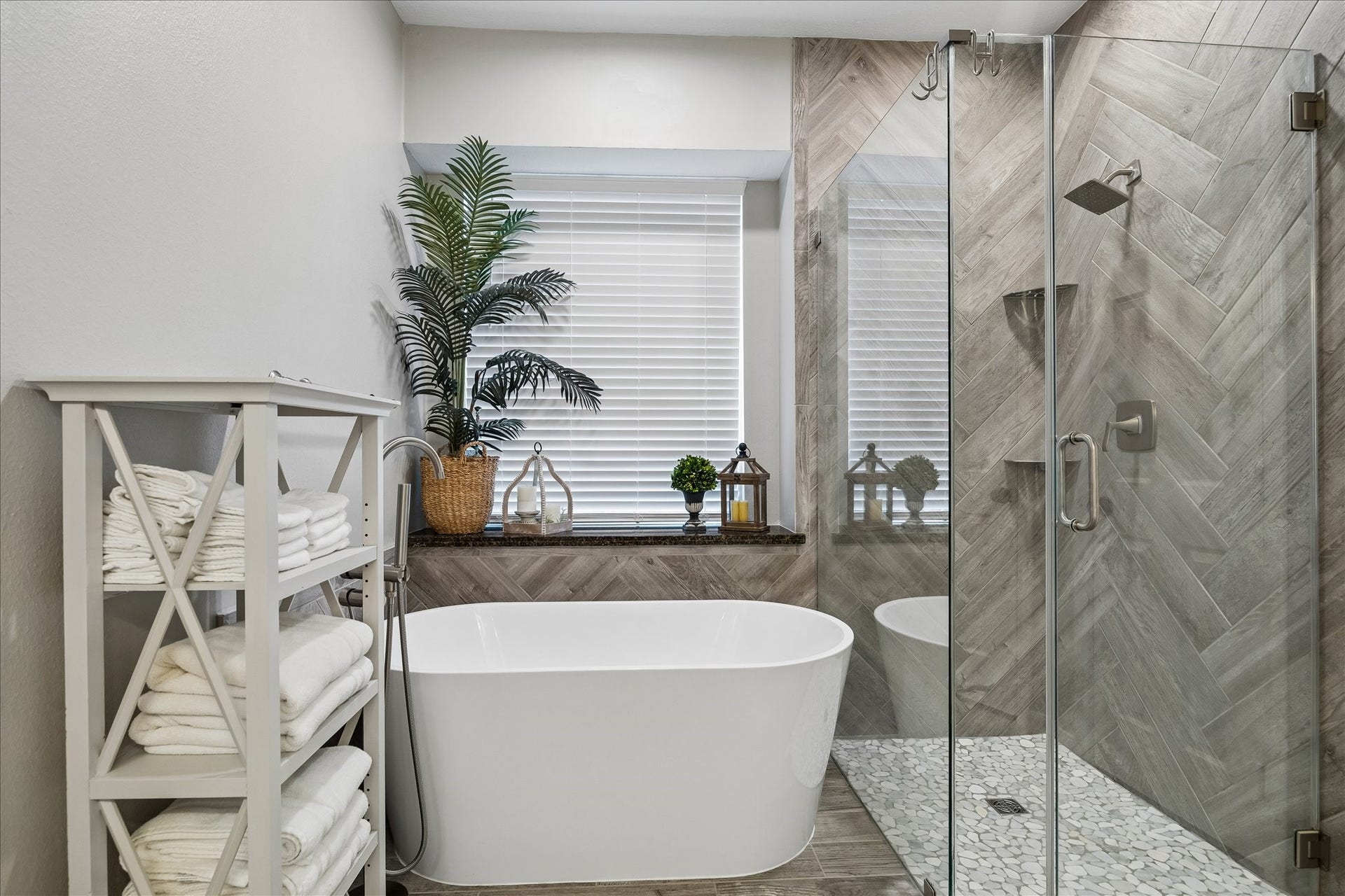 2411 Kings Lodge Drive, Kingwood, TX 77345 Luxurious bathroom featuring a freestanding tub, elegant glass shower, and stylish wood-patterned tiles, complemented by natural light and tasteful decor.