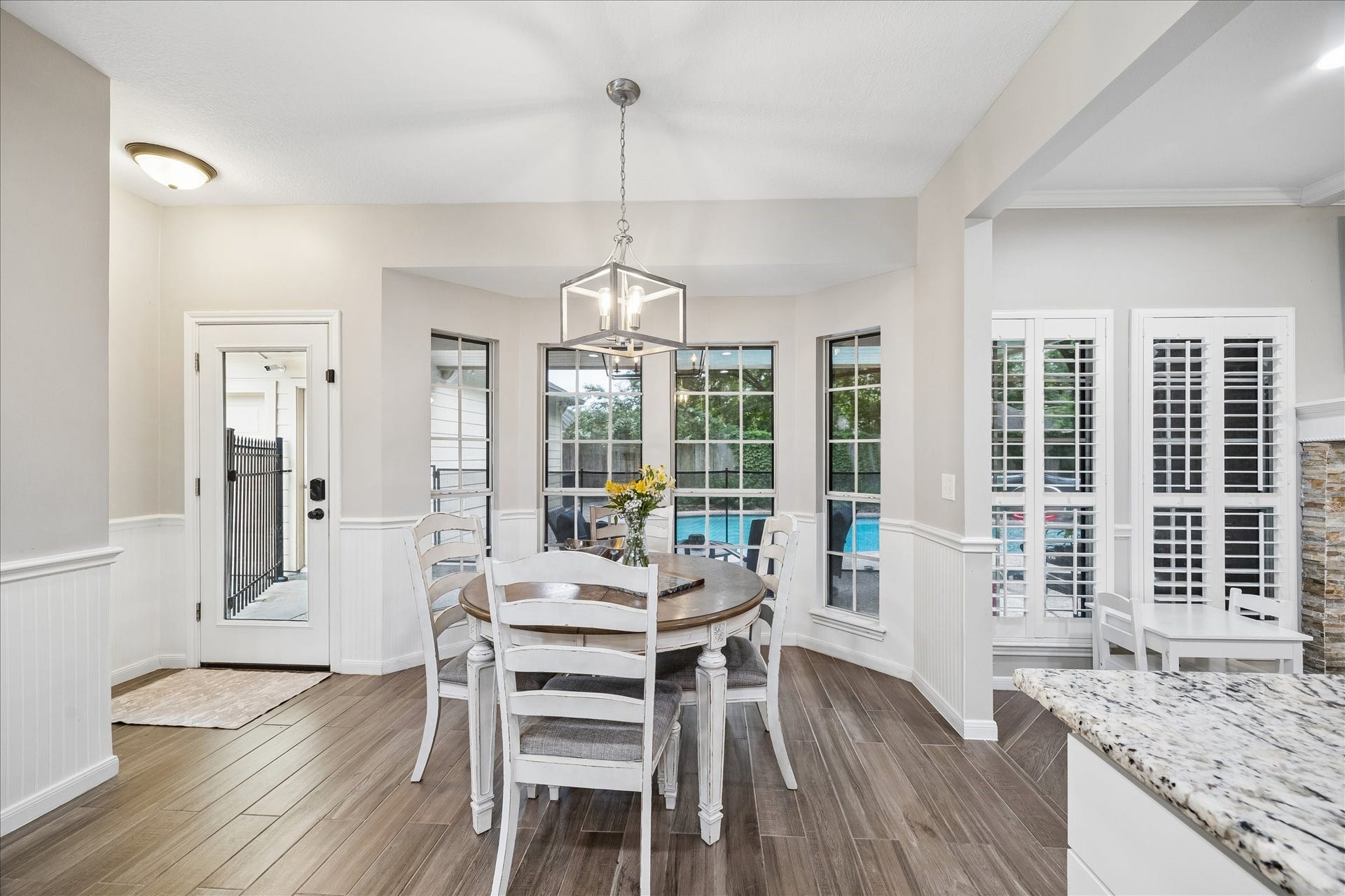 2411 Kings Lodge Drive, Kingwood, TX 77345 Bright dining area with large windows offers a view of the pool, featuring elegant flooring and a modern light fixture, creating a welcoming atmosphere.