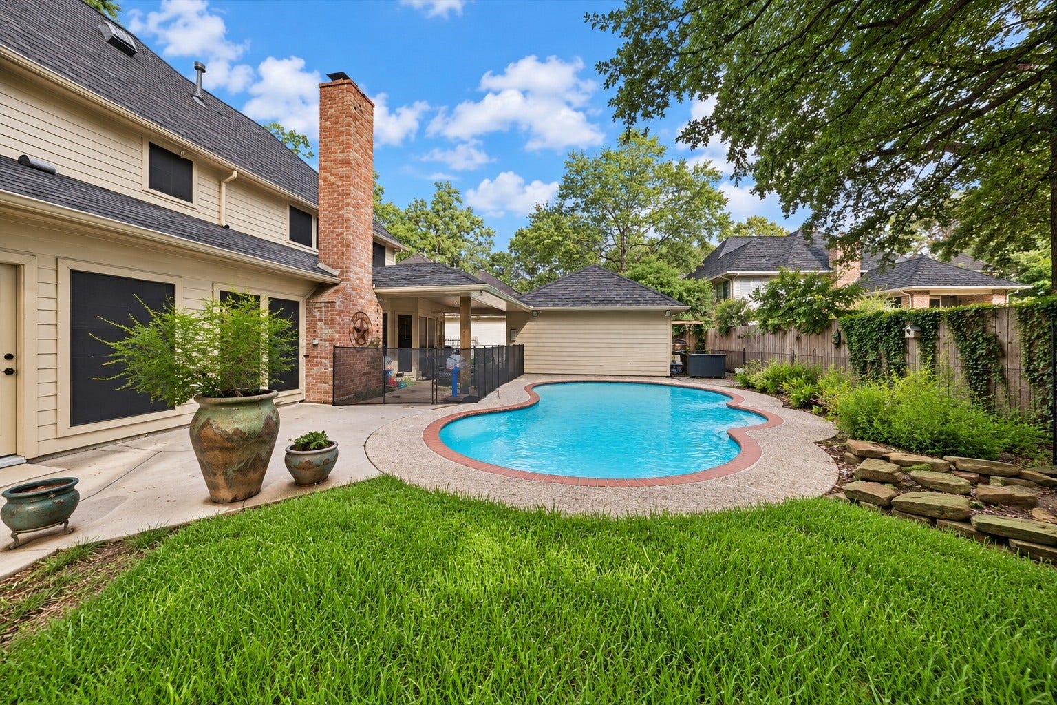 2411 Kings Lodge Drive, Kingwood, TX 77345 Charming backyard oasis featuring a sparkling pool, lush greenery, and a spacious patio perfect for outdoor entertaining.
