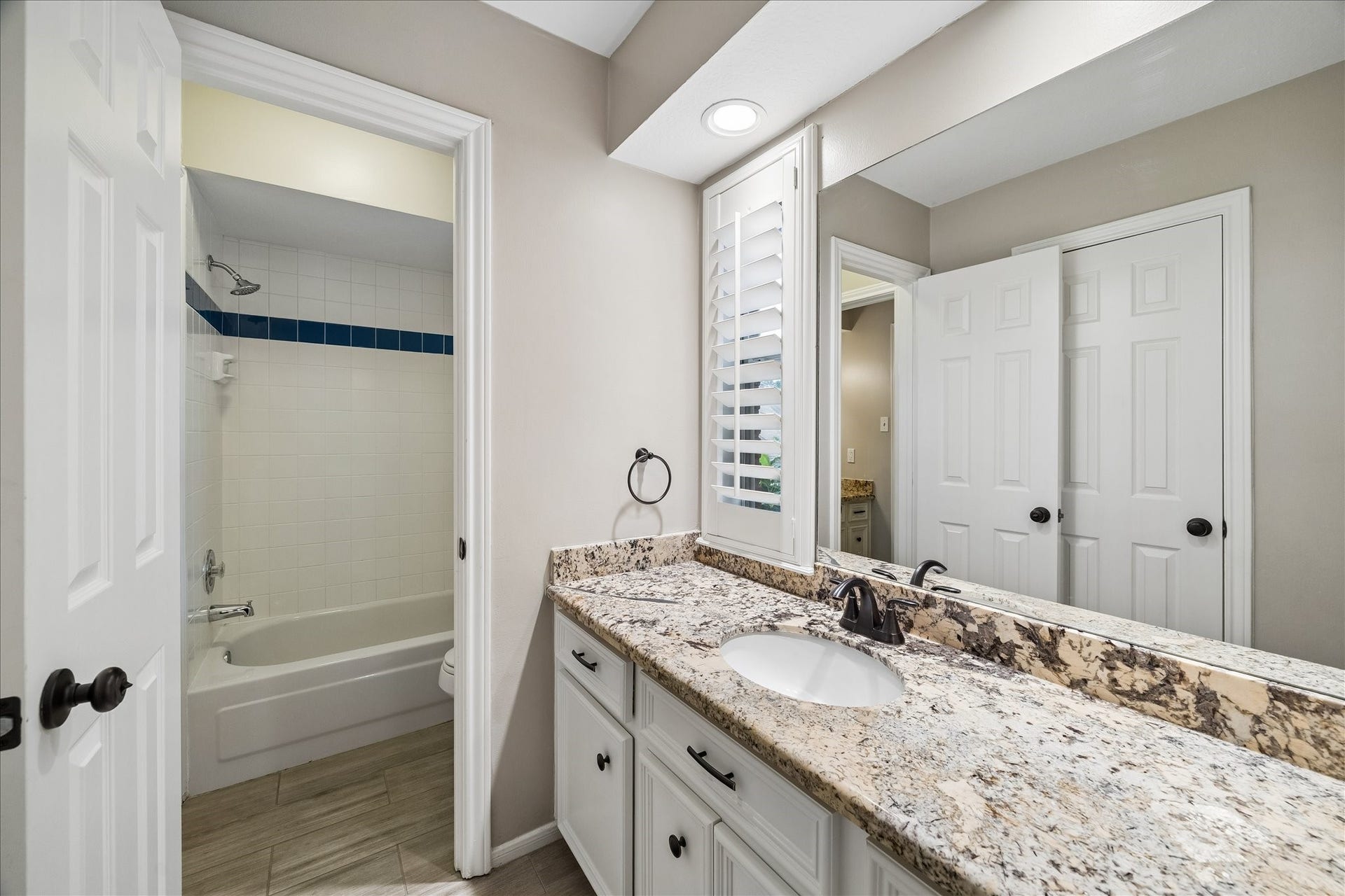 2411 Kings Lodge Drive, Kingwood, TX 77345 Elegant jack-and-jill bathroom featuring updated granite countertop, spacious sink, and ample storage, complemented by a full bathtub with classic tile accents.