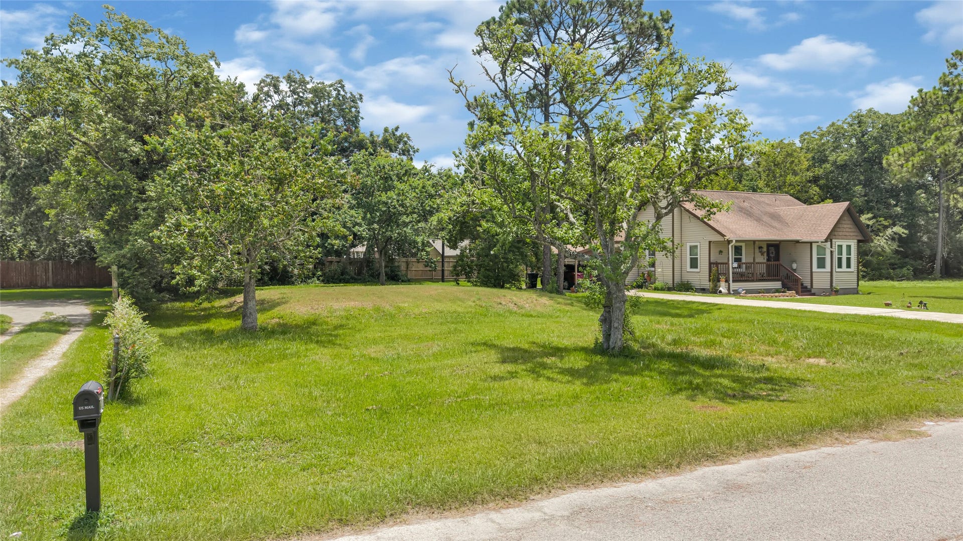 6519 Pinecrest Drive, Hitchcock, TX 77563 Charming single-story home nestled on a spacious, lush green lot with mature trees, offering ample outdoor space and privacy.