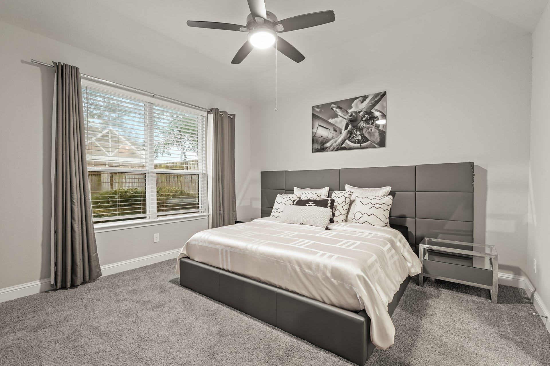 1710 Forest Mist Drive, Missouri City, TX 77459 A bright and welcoming primary bedroom, showing off a great layout for a main suite. The room has a modern, cohesive look with its neutral grey walls, white trim, and plush dark carpeting. A large double window provides a nice view of the outside and lets in great natural light. The high vaulted ceiling adds an open, airy feel, making this primary bedroom a comfortable and inviting retreat at the end of the day.