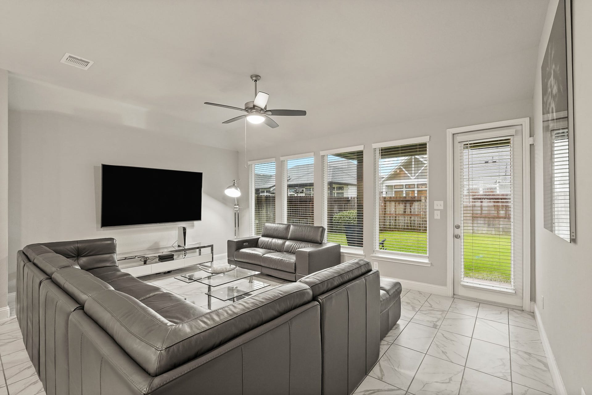 1710 Forest Mist Drive, Missouri City, TX 77459 An open and inviting living room boasting premium marble-look tile floors, tall windows for abundant natural light, a recessed ceiling with a modern fan.