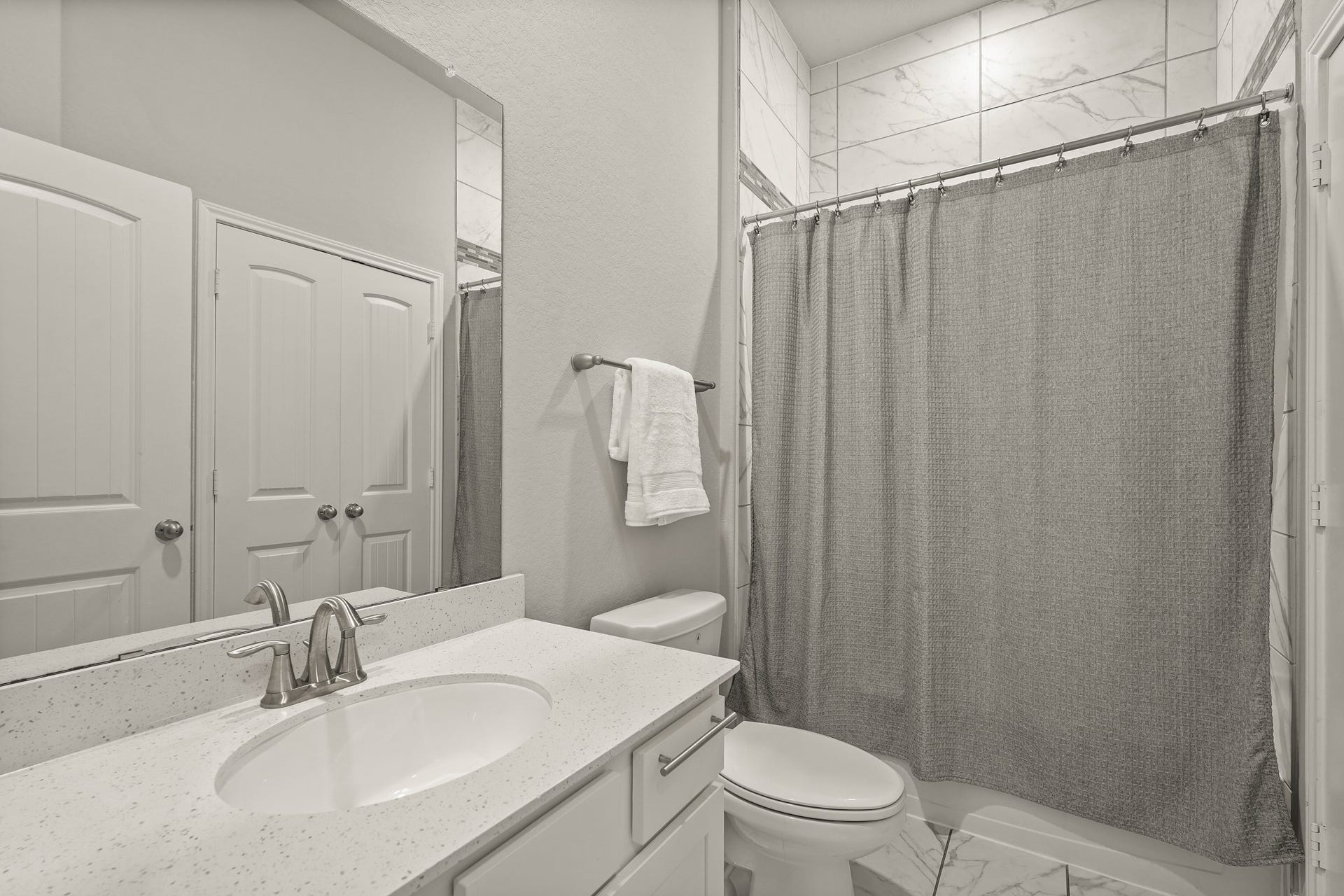 1710 Forest Mist Drive, Missouri City, TX 77459 This beautifully appointed full bathroom features a crisp white vanity topped with a subtle quartz countertop, an under-mount oval sink, and a contemporary brushed nickel faucet. The tub/shower combination is framed by high-end, large-format marble-patterned wall tile.