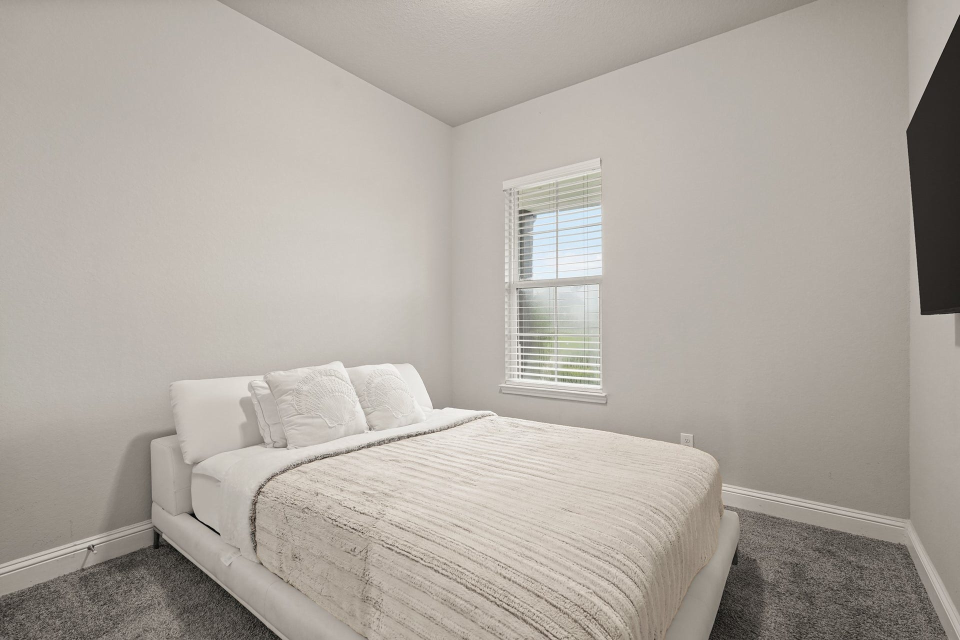 1710 Forest Mist Drive, Missouri City, TX 77459 This cozy secondary bedroom offers a bright and inviting atmosphere with soft neutral tones and abundant natural light. The room features plush carpeting, crisp white trim, creating a clean and modern aesthetic. A large window with blinds allows natural light to fill the space while offering views of the outdoors.