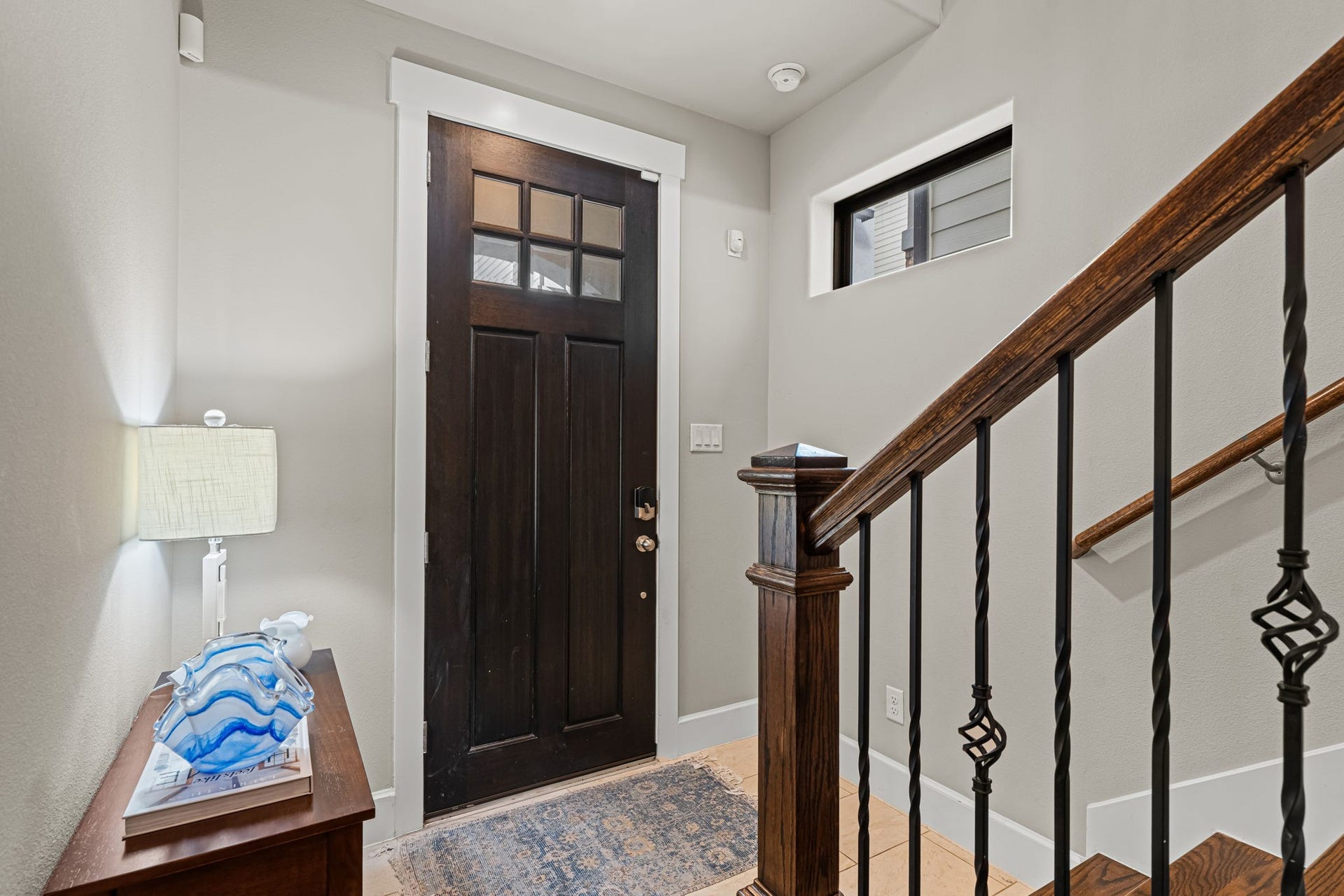 868 Wakefield Drive, #B, Houston, TX 77018 Daylight filters through the transom above the front door, illuminating a welcoming pocket of the foyer. A warm wood handrail and decorative ironwork carry the home's traditional detailing through the entry.