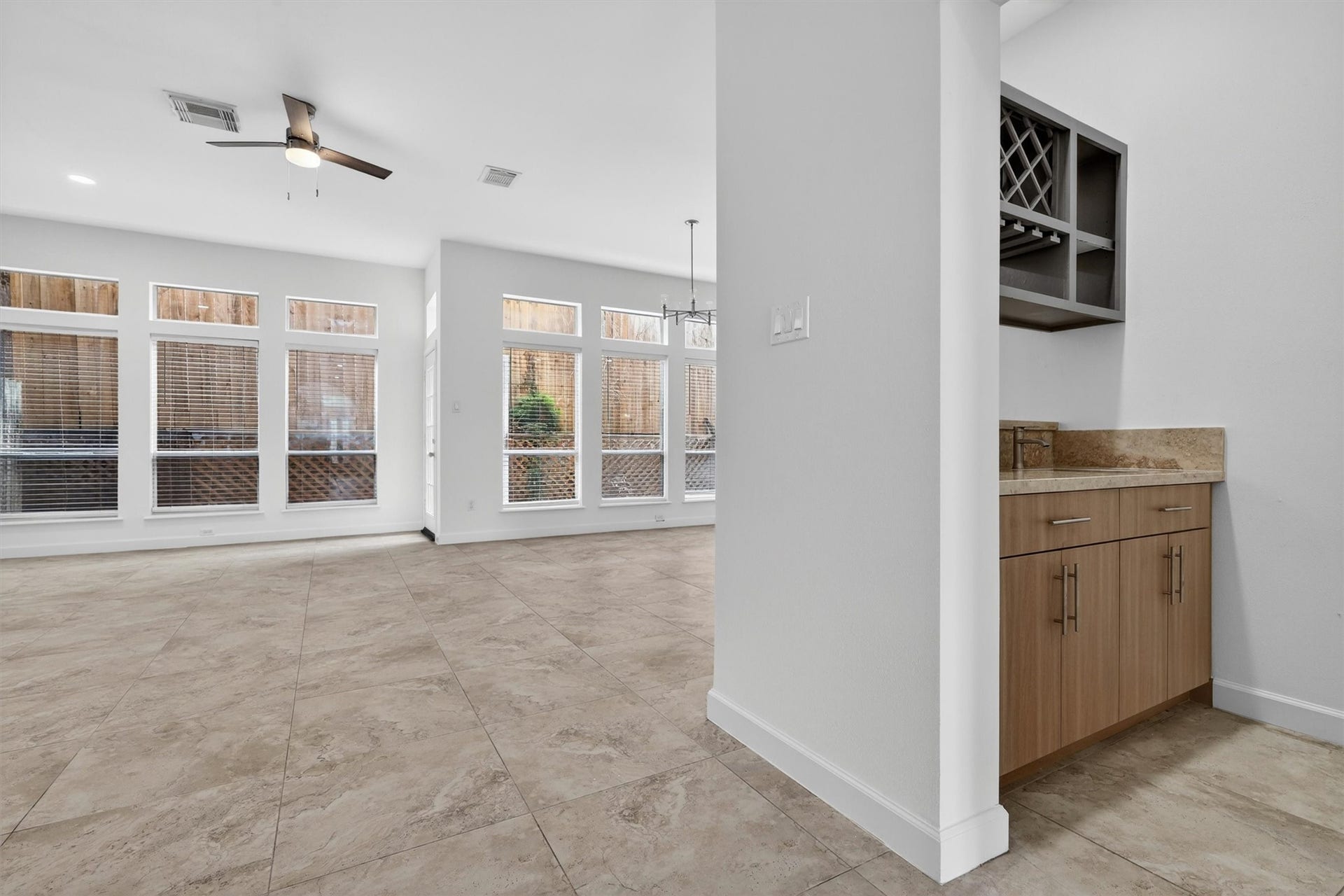 4720 Post Oak Timber Drive, #23, Houston, TX 77056 Bright and airy open-concept living and dining area with soaring ceilings, oversized windows, and abundant natural light. Features include oversized tile flooring, modern wet bar with wine storage, recessed lighting, and neutral designer finishes. Spacious layout offers seamless indoor-outdoor flow and is ideal for entertaining.