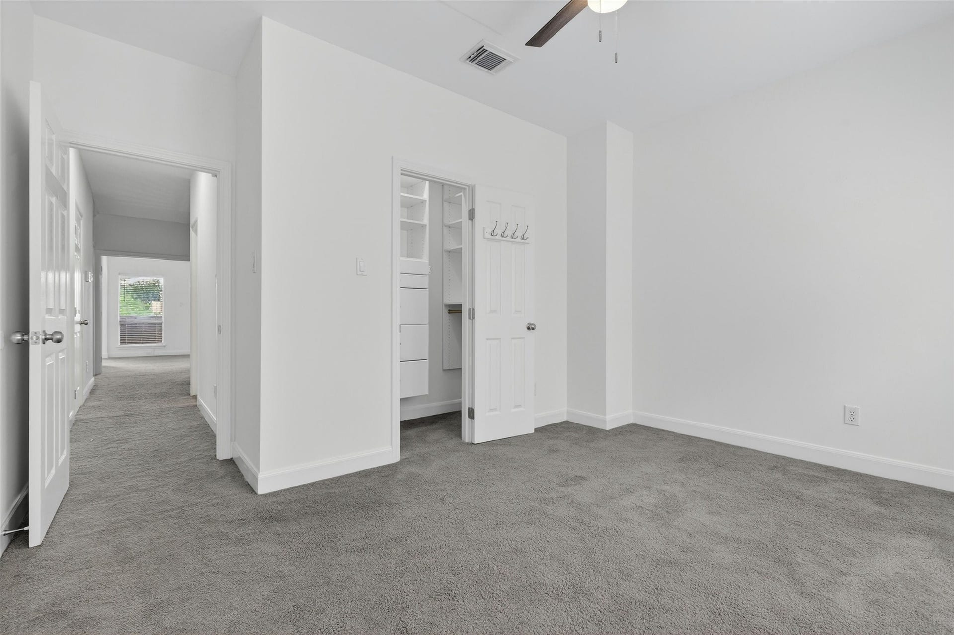 4720 Post Oak Timber Drive, #23, Houston, TX 77056 Spacious secondary bedroom featuring plush carpet, ceiling fan, neutral designer paint, and custom walk-in closet with built-in storage. Bright and versatile layout offers comfort and functionality, perfect for guests, family, or a home office setup.