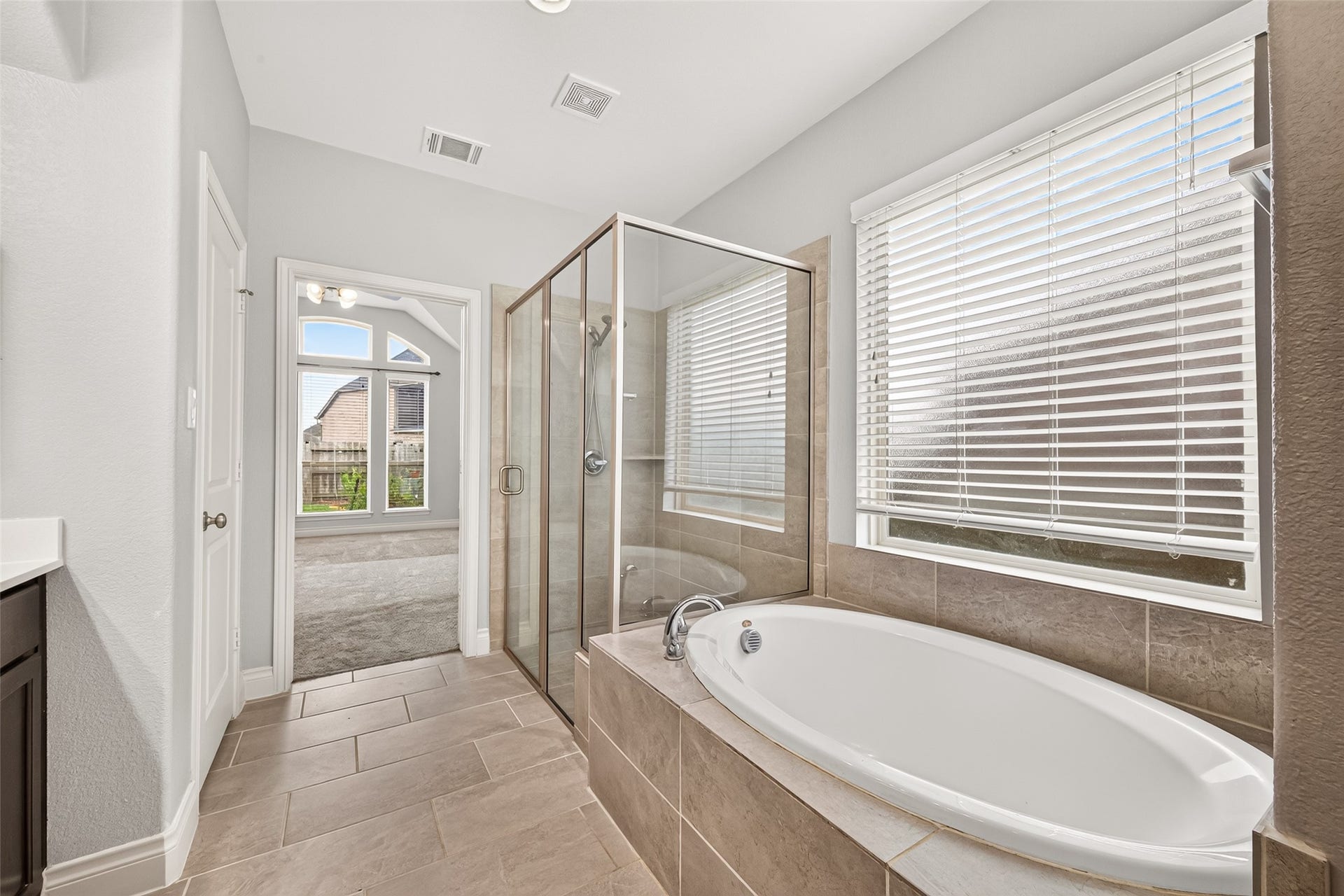 23335 Peareson Bend Lane, Richmond, TX 77469 Elegant en-suite bath featuring a double vanity, relaxing soaking tub, and a glass-enclosed walk-in shower, creating a luxurious spa-like retreat.