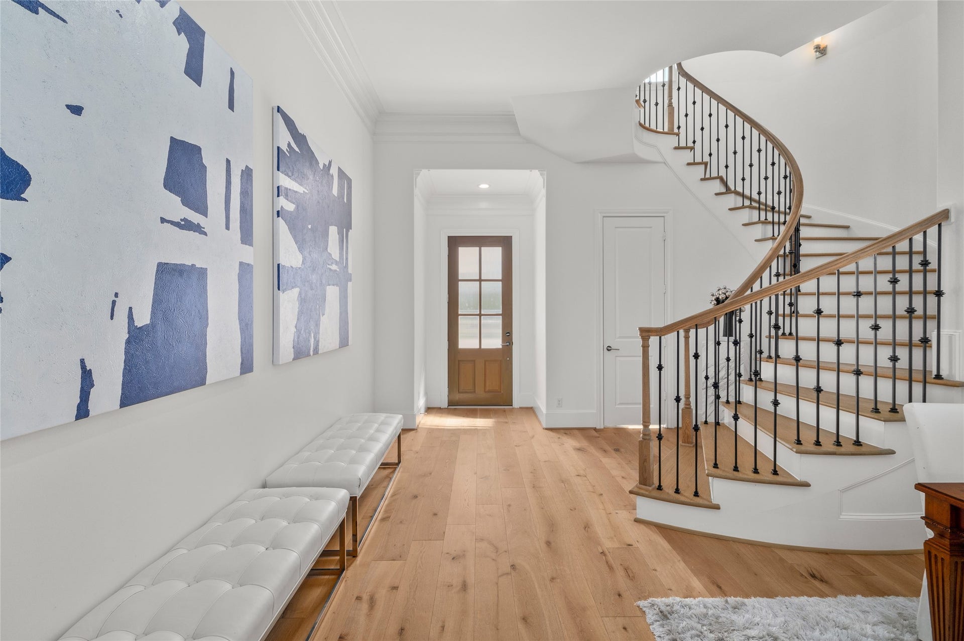 7554 Little Caprese Lane, Houston, TX 77055 An elegant entryway featuring wide-plank hardwood floors, refined crown molding, and a sweeping curved staircase with wrought-iron balusters and natural wood accents.