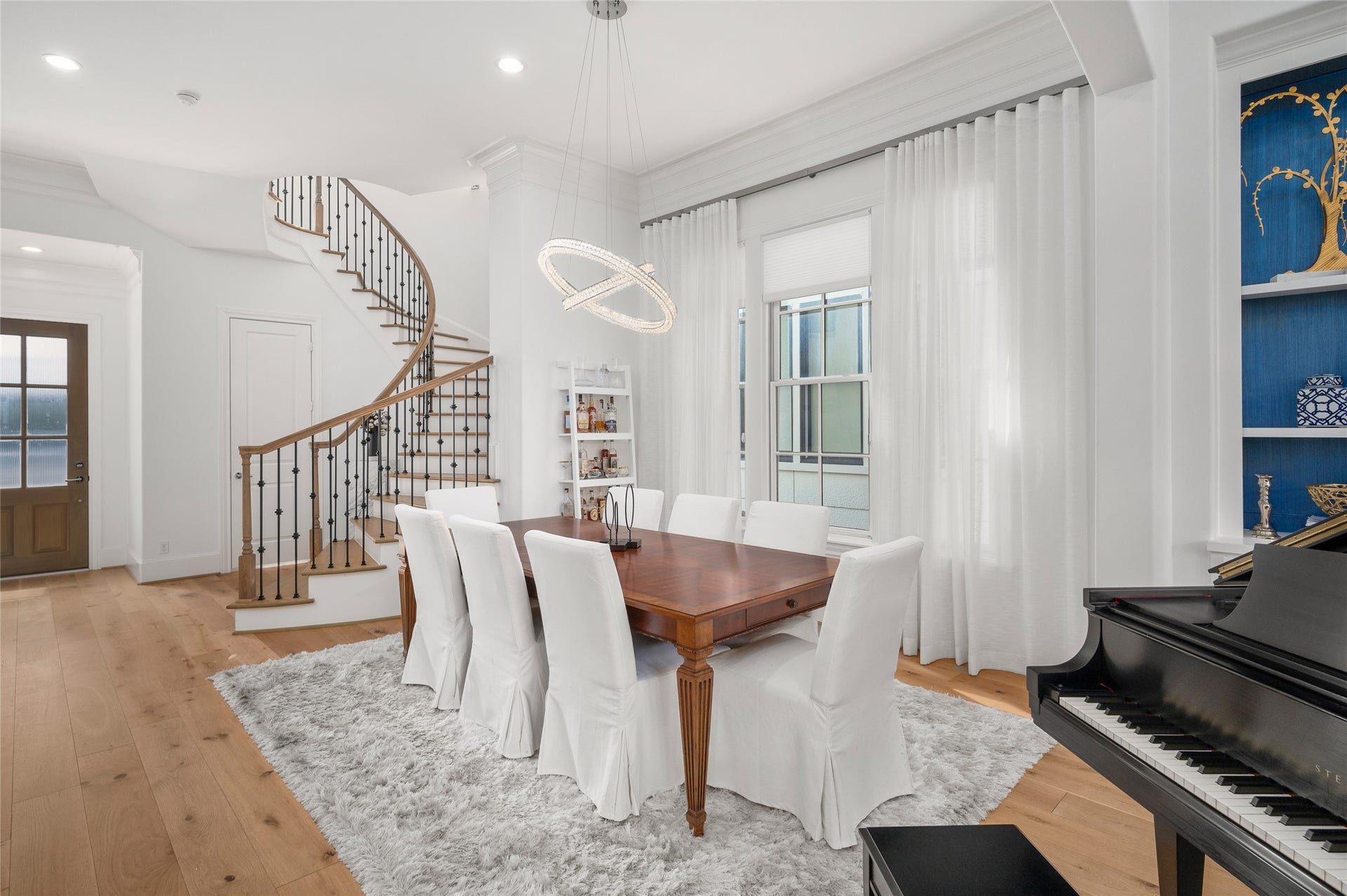 7554 Little Caprese Lane, Houston, TX 77055 A second perspective captures the curved staircase with wrought-iron detailing and the dining room's understated architectural finishes.