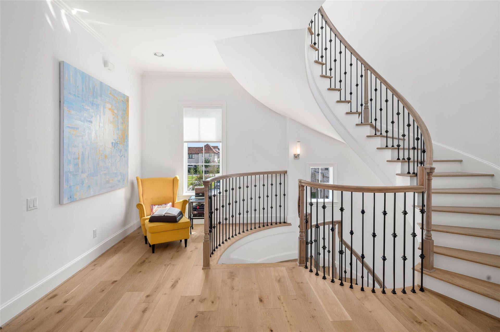7554 Little Caprese Lane, Houston, TX 77055 Architectural curved staircase with natural wood handrails, iron balusters, and an adjacent sitting nook.