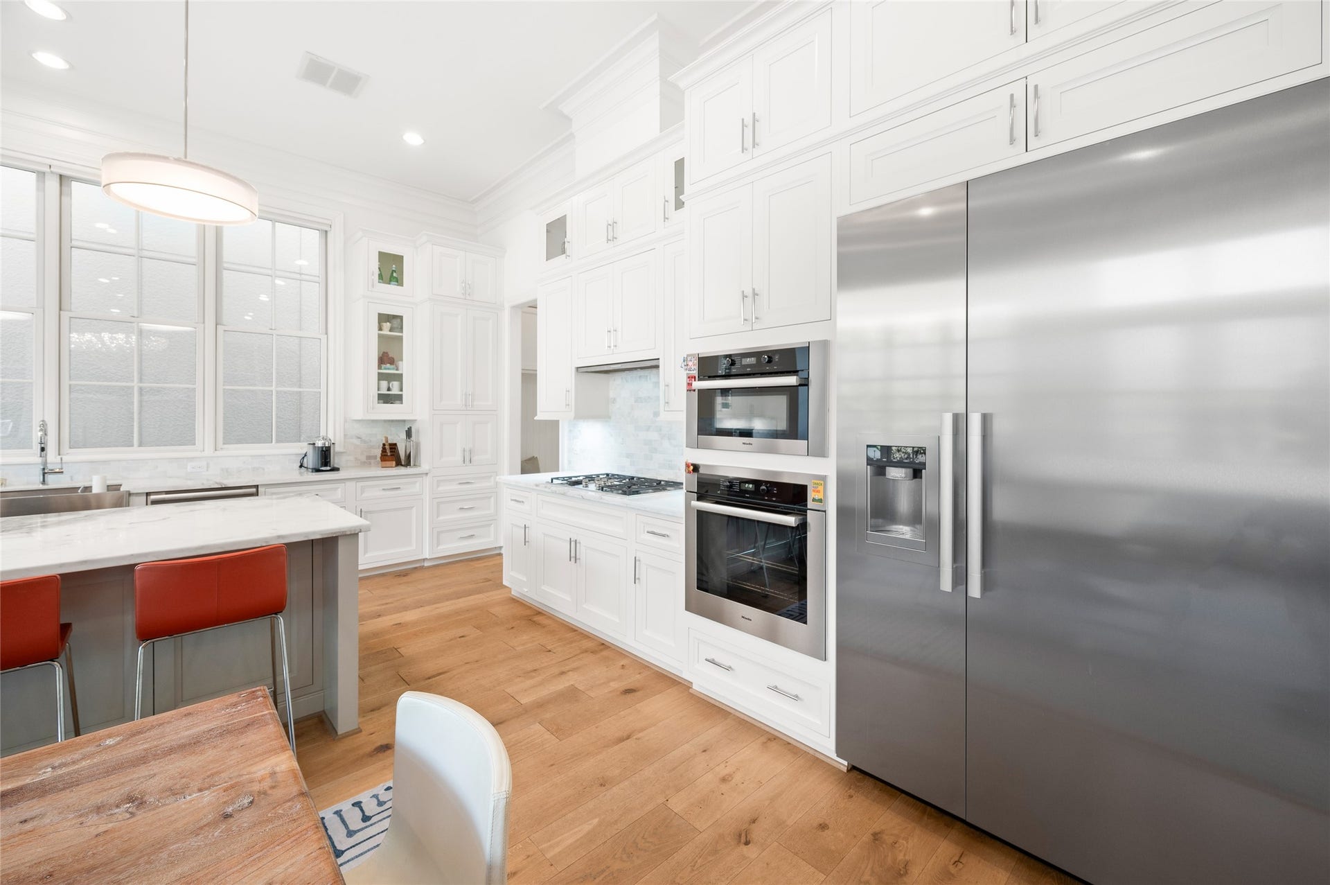 7554 Little Caprese Lane, Houston, TX 77055 Miele steel appliances, including a built-in oven, microwave, gas cooktop, and French-door refrigerator, are set within floor-to-ceiling custom cabinetry.