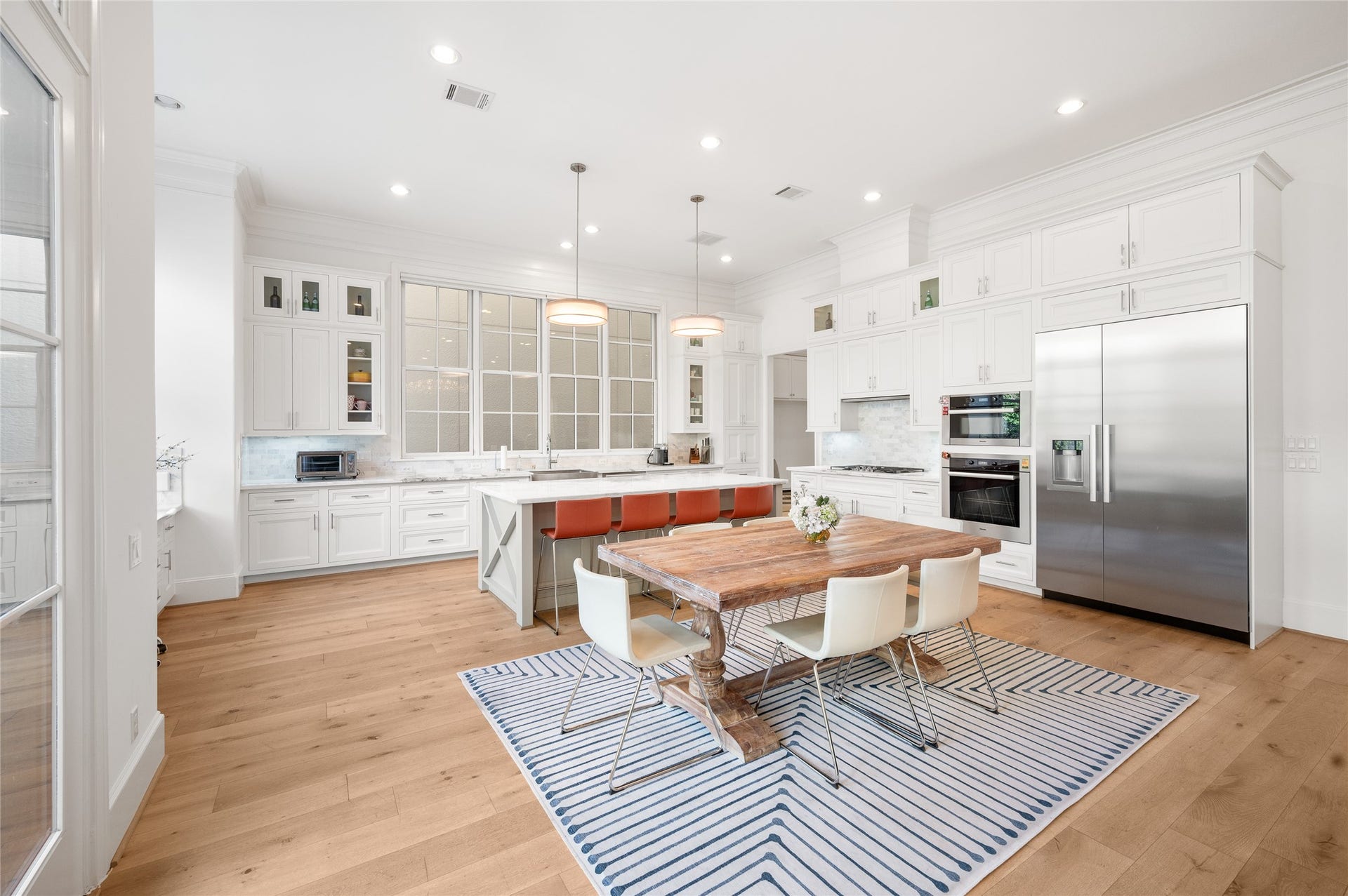 7554 Little Caprese Lane, Houston, TX 77055 Generously proportioned kitchen with ceiling-height cabinetry, an oversized island, marble countertops, stainless steel appliances, and a dedicated breakfast area.