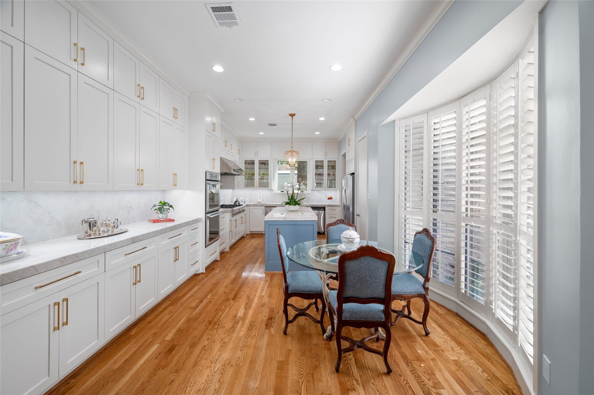[Gathering Kitchen]
View into the gathering kitchen from the dining room. Note breakfast alcove with bow window at right, custom cabinets and hardware, and quartz countertops.