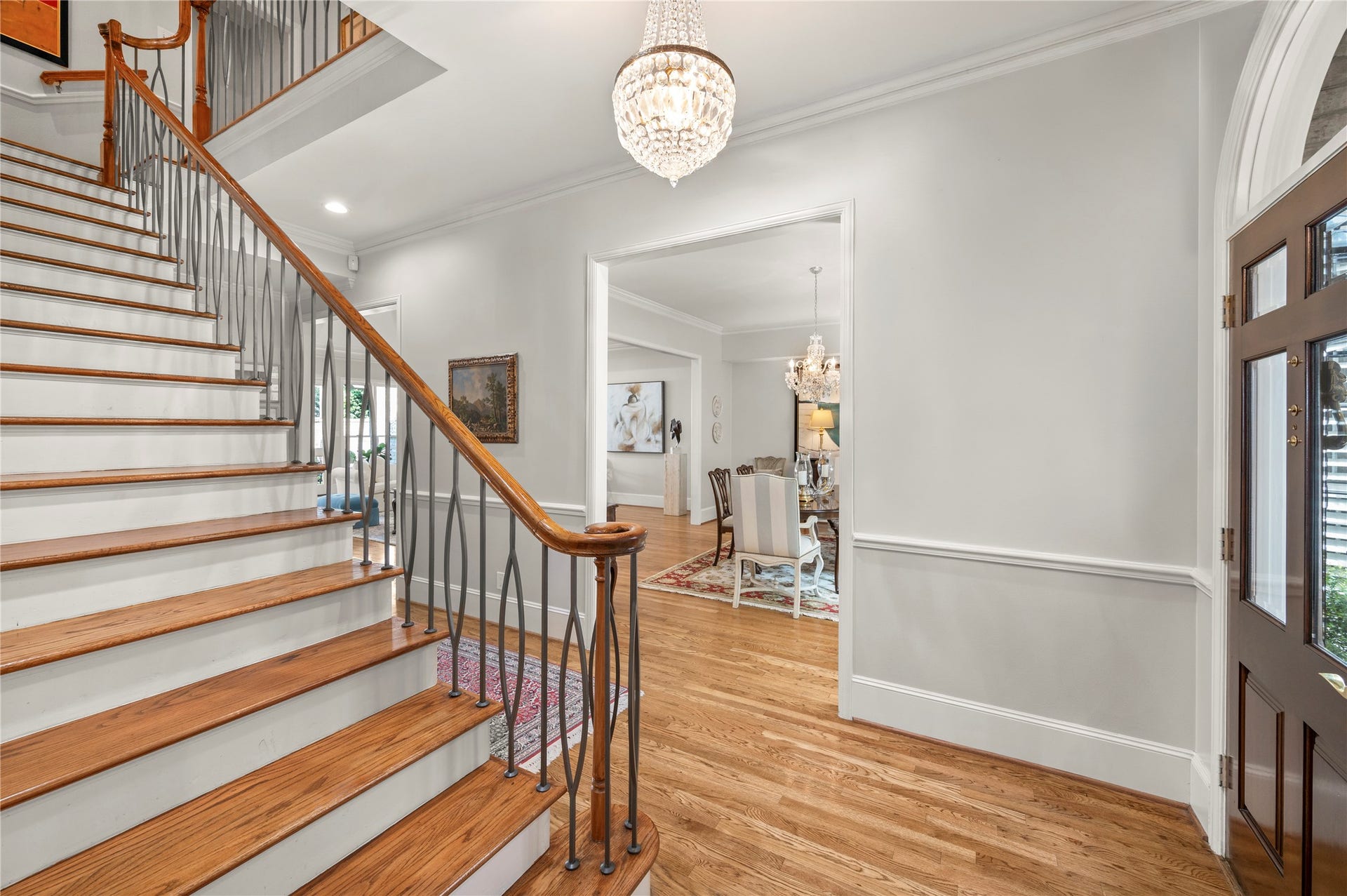 [Foyer]
Polished hardwoods extend across both floors. The foyer opens to the formal rooms through cased openings; solid double doors open to the study at left of this magnificent staircase (not shown).
