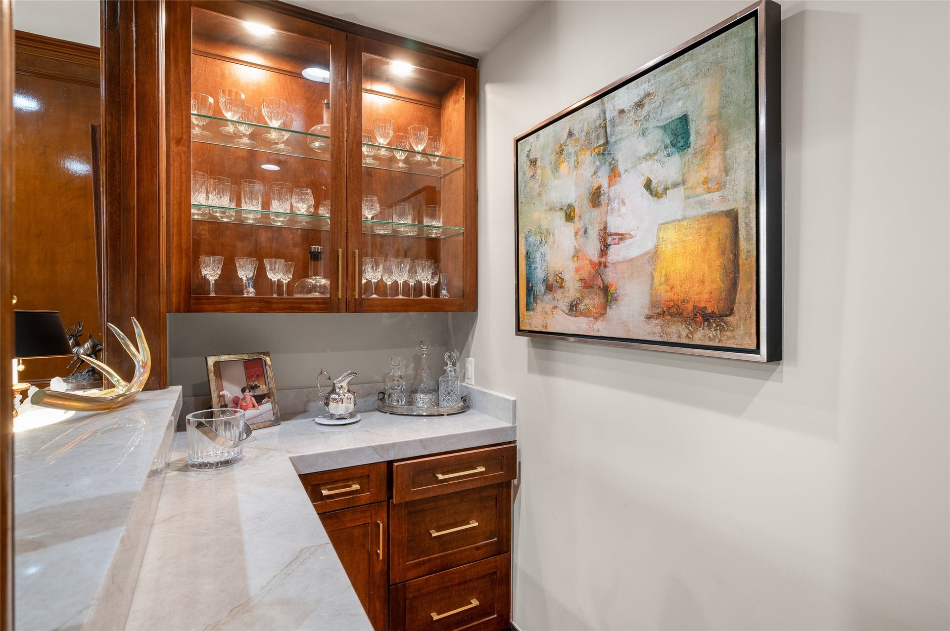 [Study]
The dry bar in the study has an interior window with serving shelf. Appointments include quartz countertops and lighted glass-faced jumper cabinets and lower cabinets.