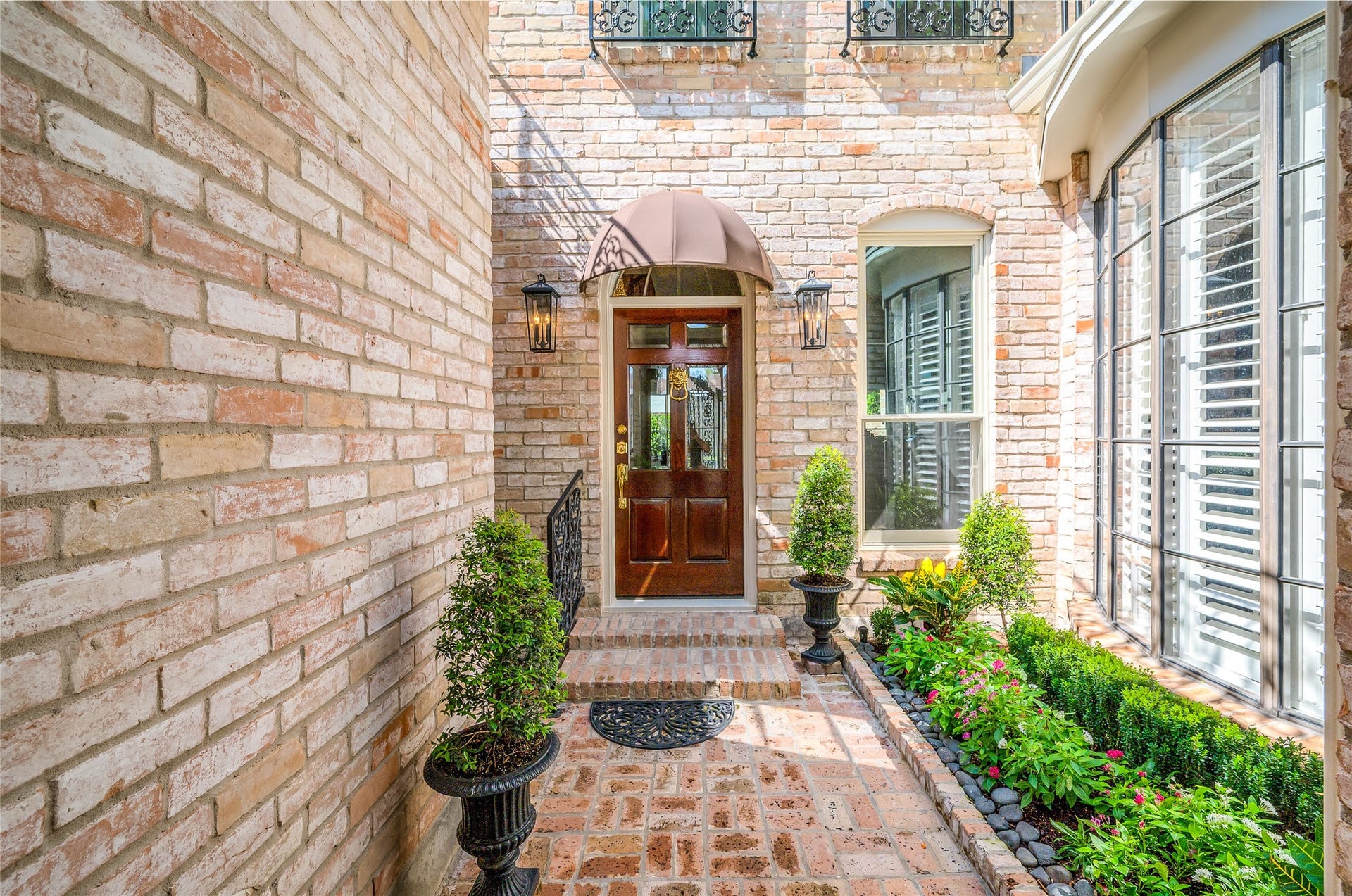 [Courtyard]
The view through the glass-peeled front door travels through the formal rooms to the lush rear patio. Bow window (right) provides pretty views from the breakfast alcove in the kitchen. Note balconet windows above front door.
