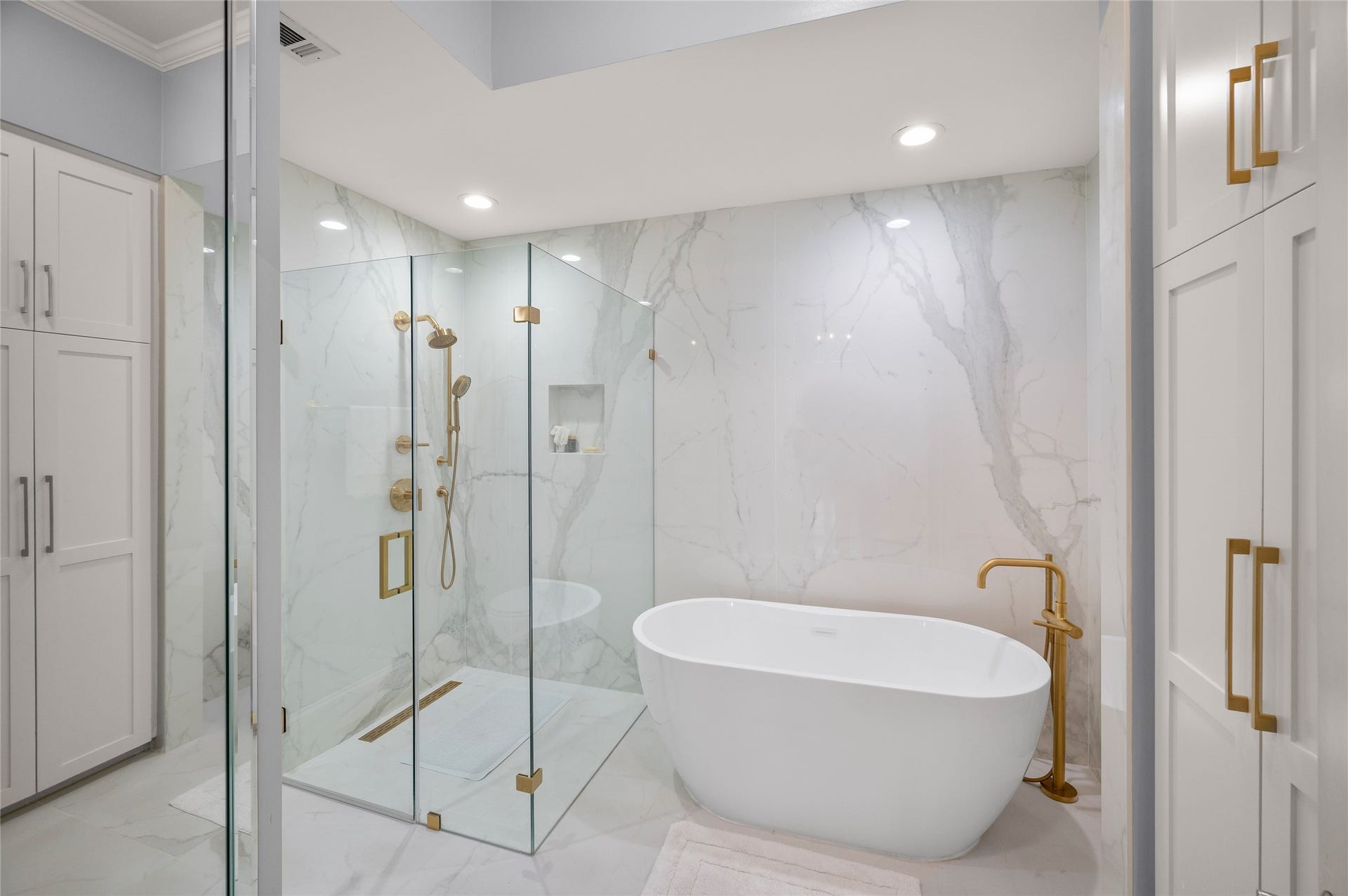 [Primary Bath]
The free-standing air tub has a floor-mounted faucet and hand-held spray. The glass enclosed shower also has a hand-held spray. Note slab porcelain wall behind tub and porcelain shower walls.