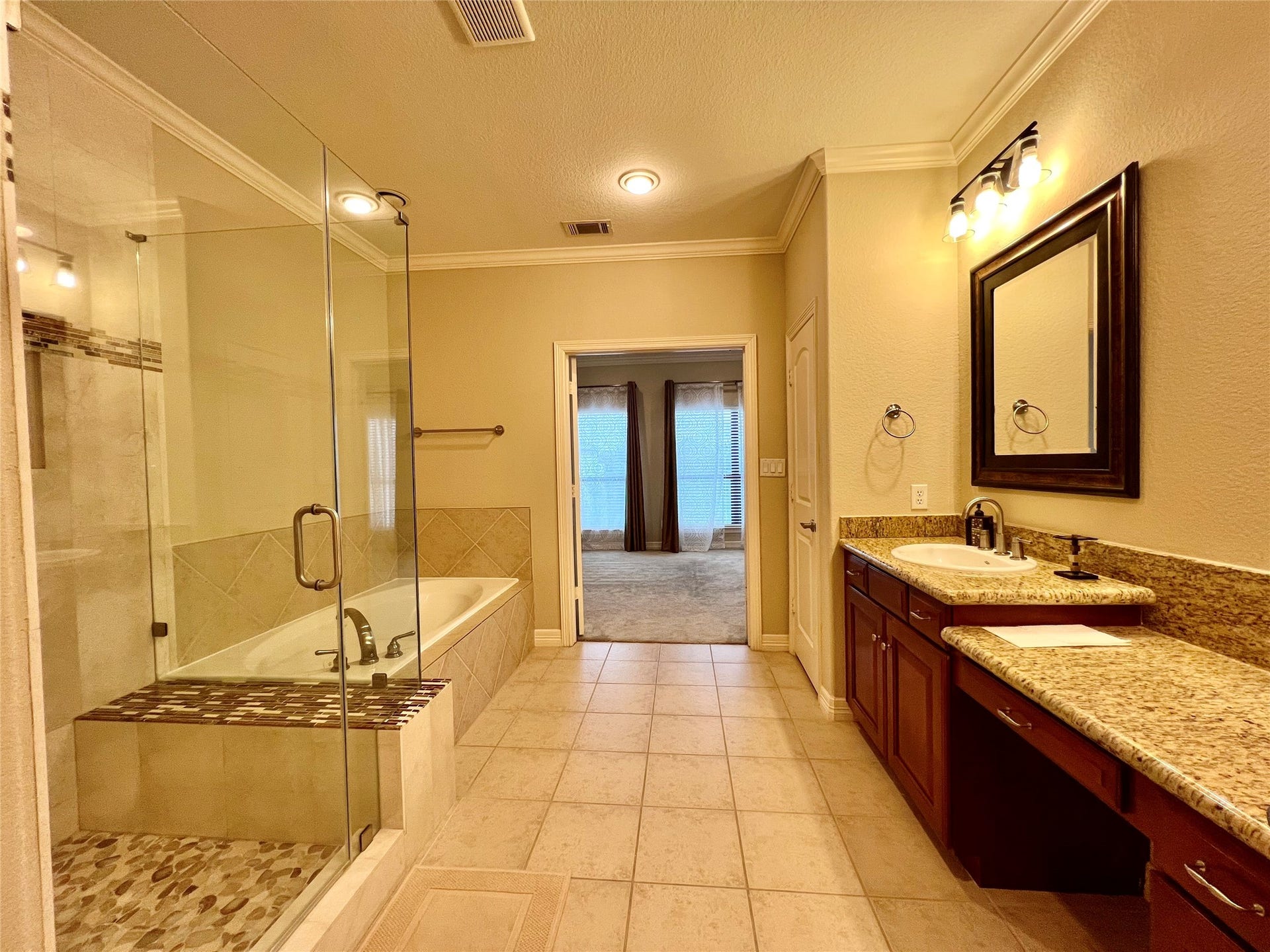 1625 Cohn Street, Houston, TX 77007 This spacious bathroom features a glass-enclosed shower and a separate bathtub, with elegant tile work throughout. It includes a large granite countertop with dual sinks and ample cabinet space.