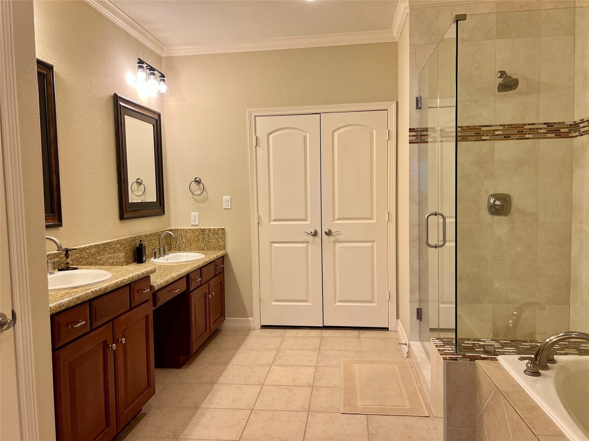 1625 Cohn Street, Houston, TX 77007 This master bathroom features a spacious layout with dual sinks, granite countertops, and wooden cabinets. It includes a glass-enclosed shower and a separate bathtub, offering a blend of functionality and elegance. There is a closet at the end of the bathroom
